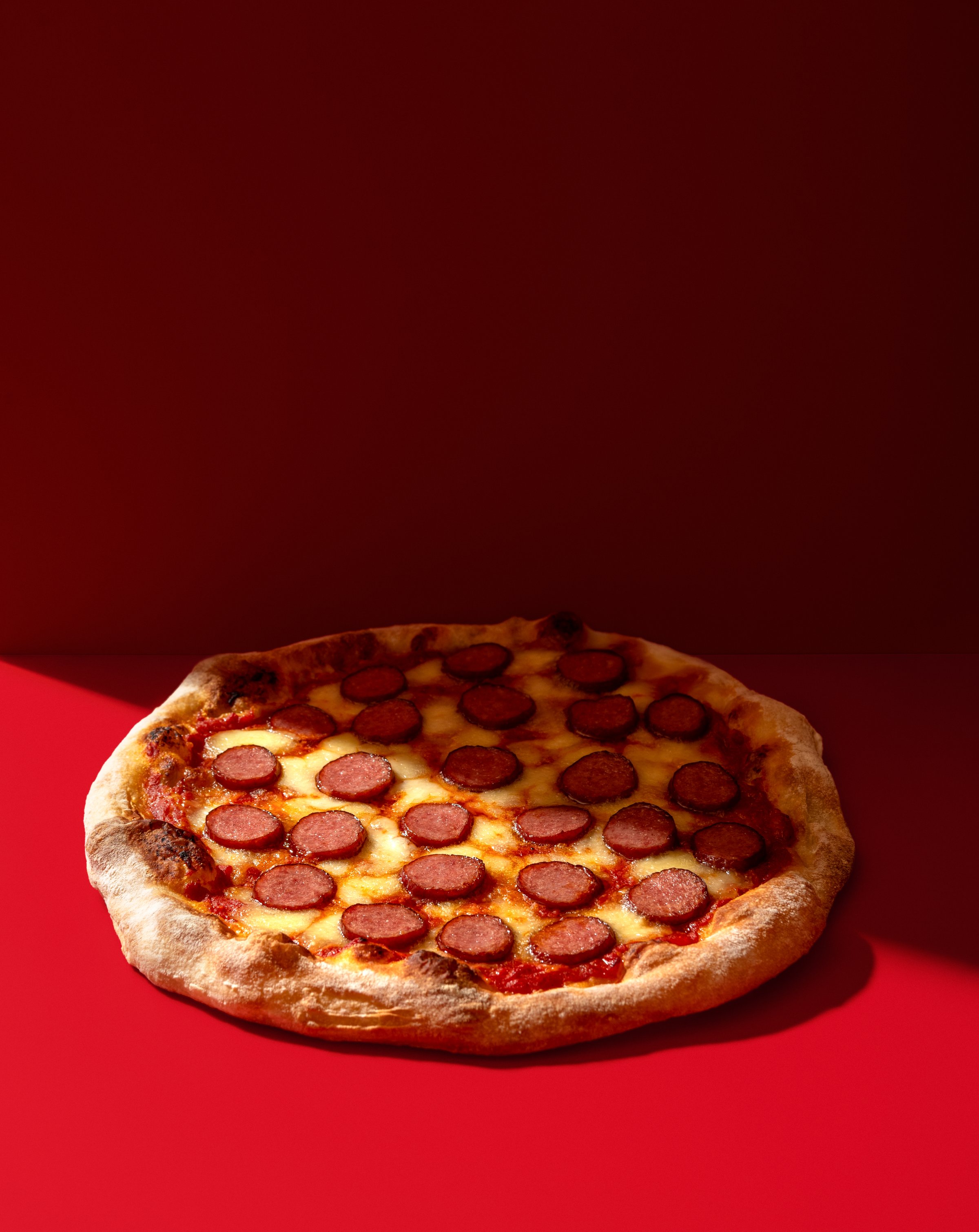 Pepperoni pizza in bright light isolated on a red background