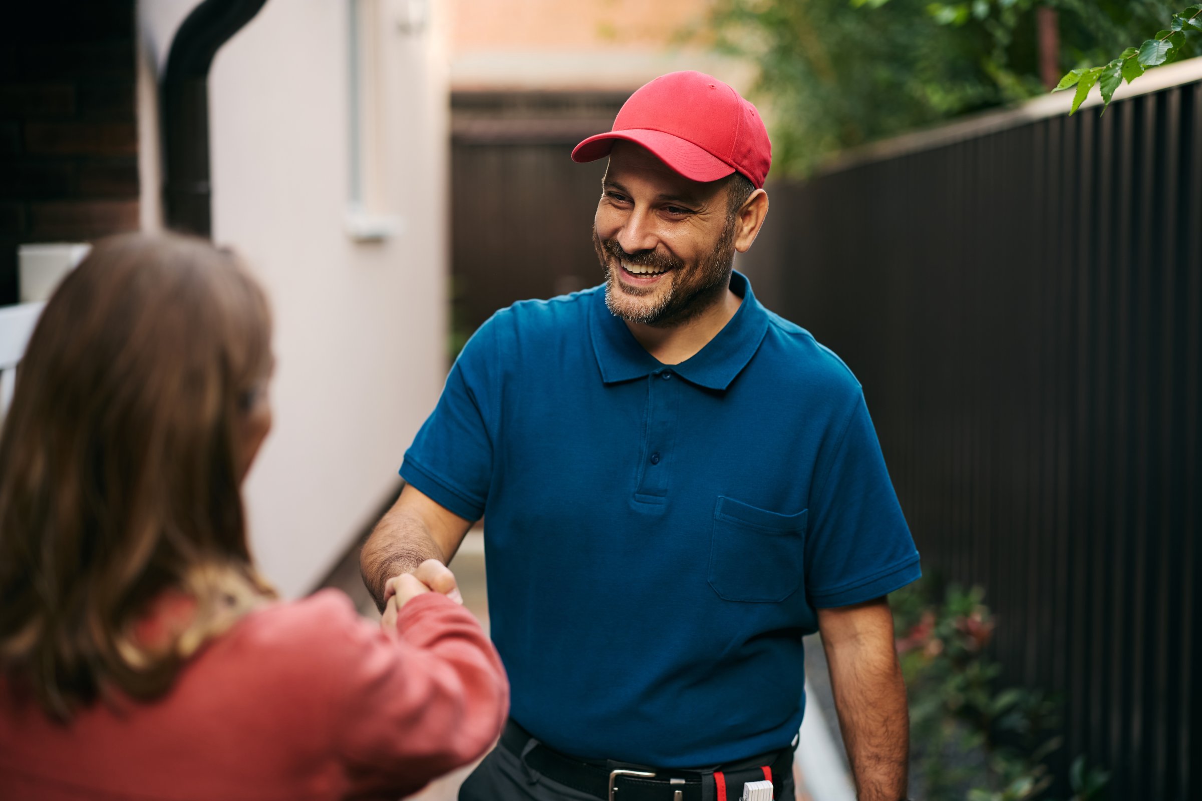 Happy handyman handshaking with his customer in the backyard.