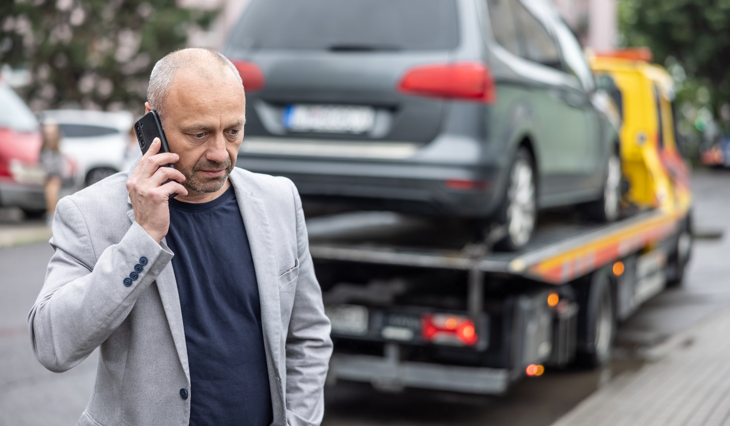 Elegant middle age business man calling insurance while towing service helping his on the road. Roadside assistance concept.