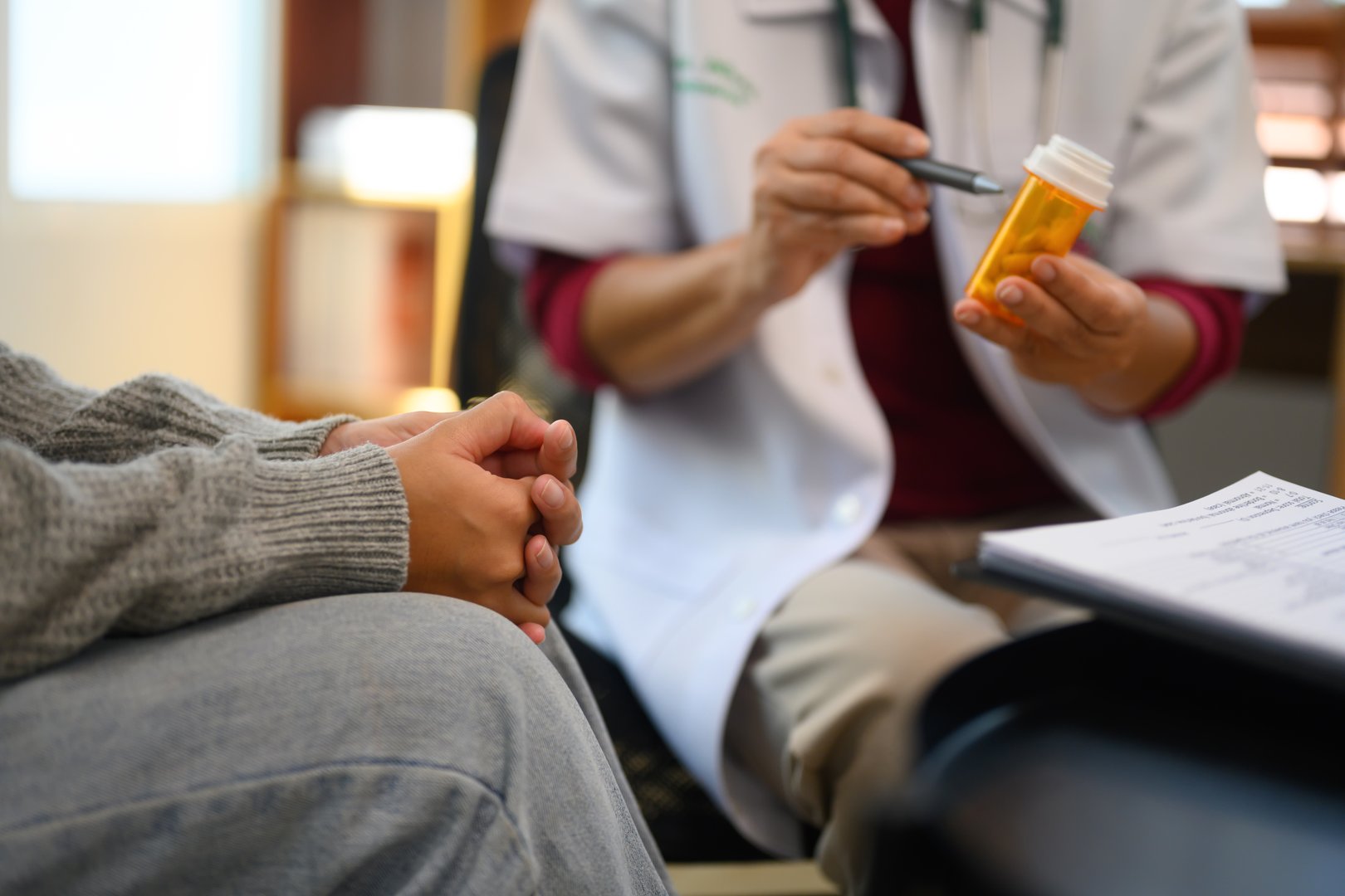 Doctor holding a bottle of prescription medication and explaining or discussing the treatment plan with patient.