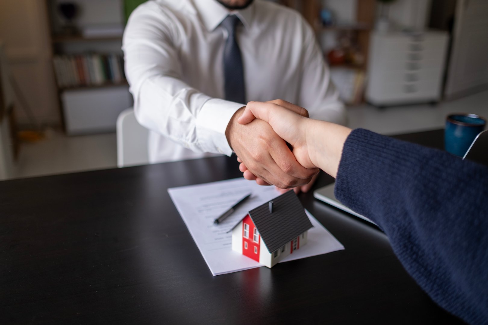 Real estate agents shake hands after the signing of the contract agreement is complete.