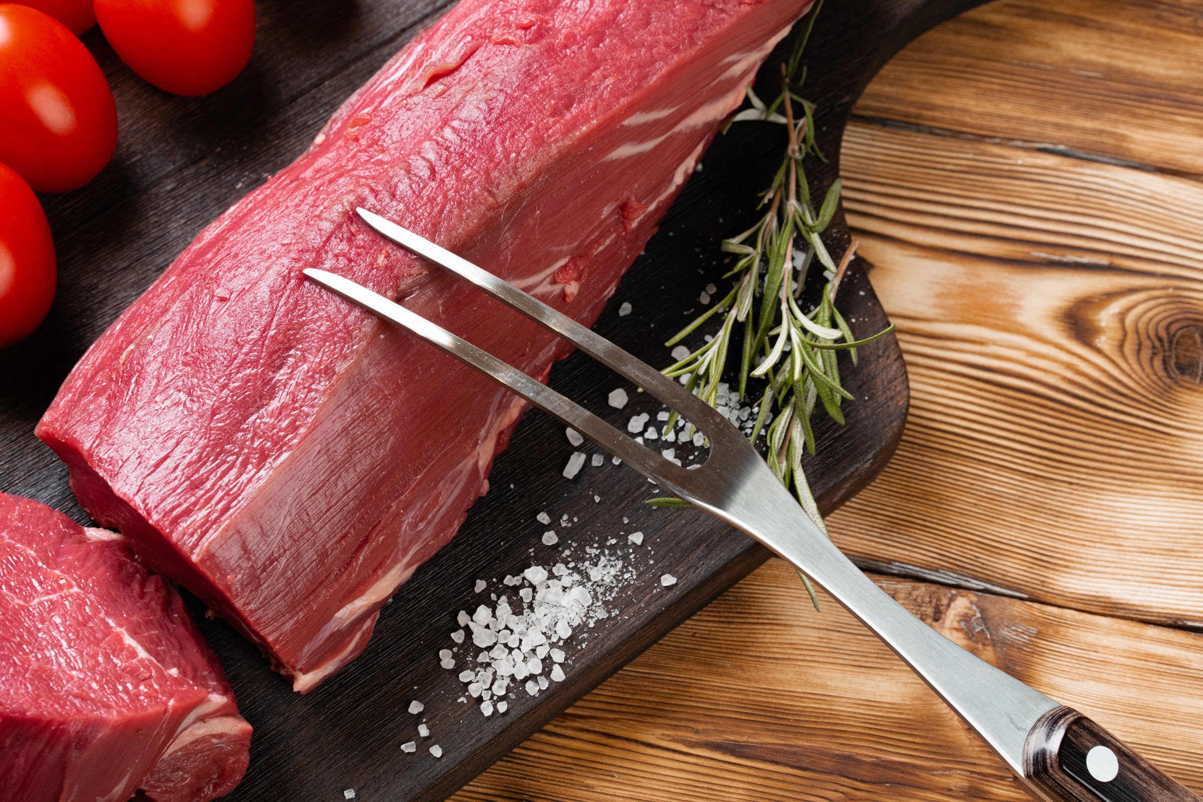 Slices raw meat fillet on wooden board, close up