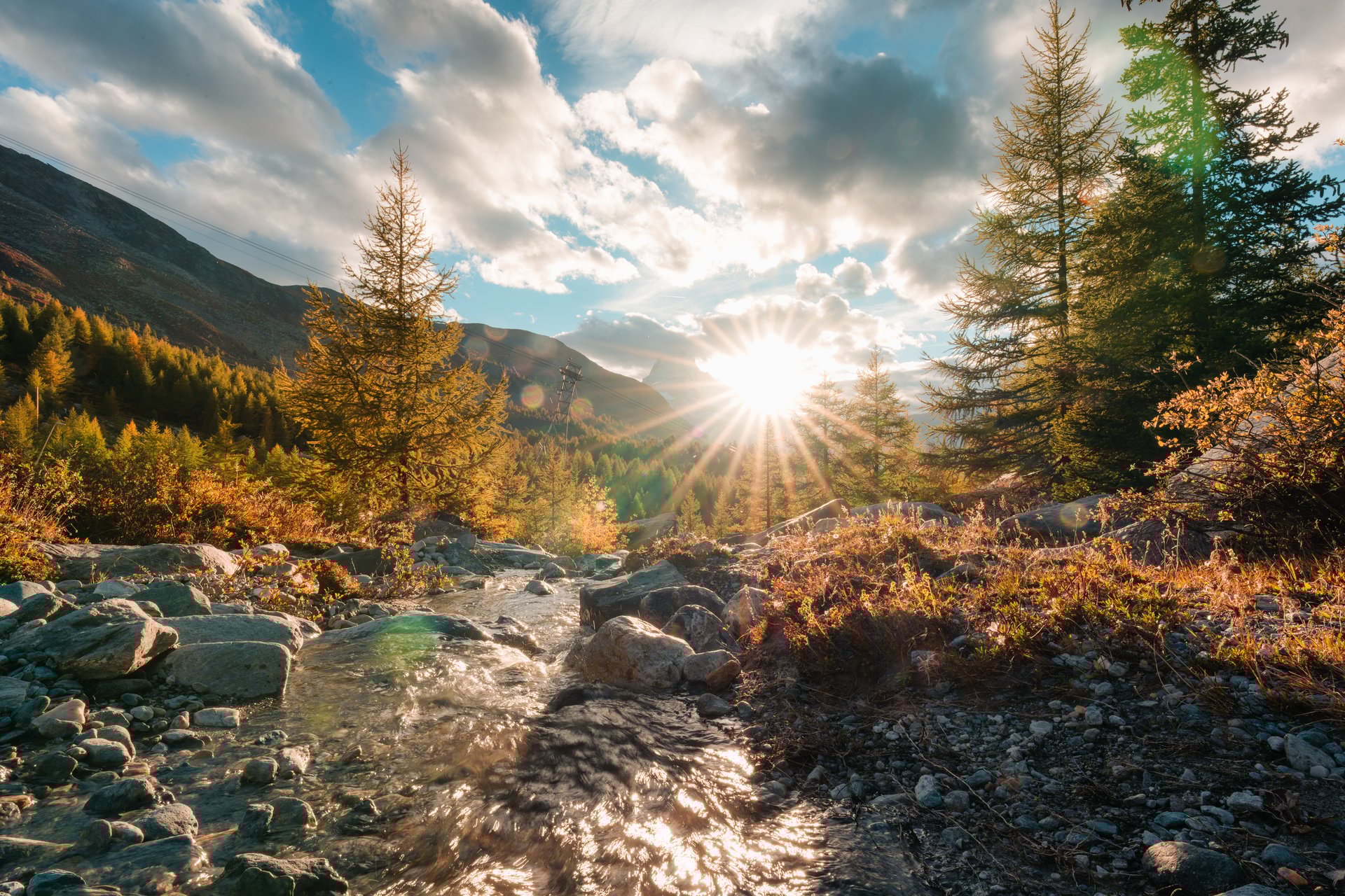 Beautiful landscape of sunset shining over Matterhorn mountain with waterfall flowing in autumn pine forest around Five Lakes at Zermatt, Switzerland