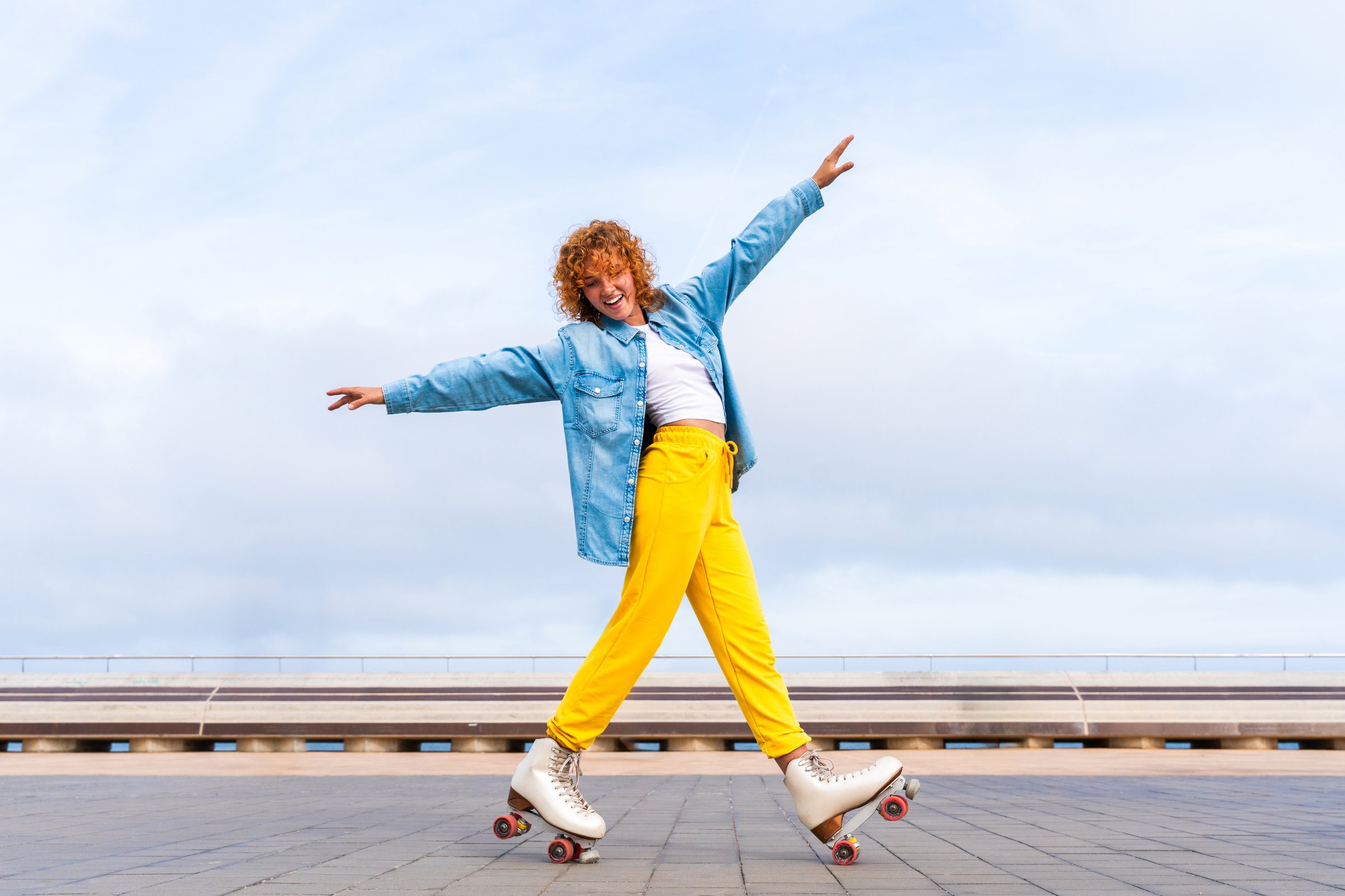 Beautiful red haired young woman with rollerskates having fun outdoors - Pretty female teenager girl with unique style riding on roller skates in the city