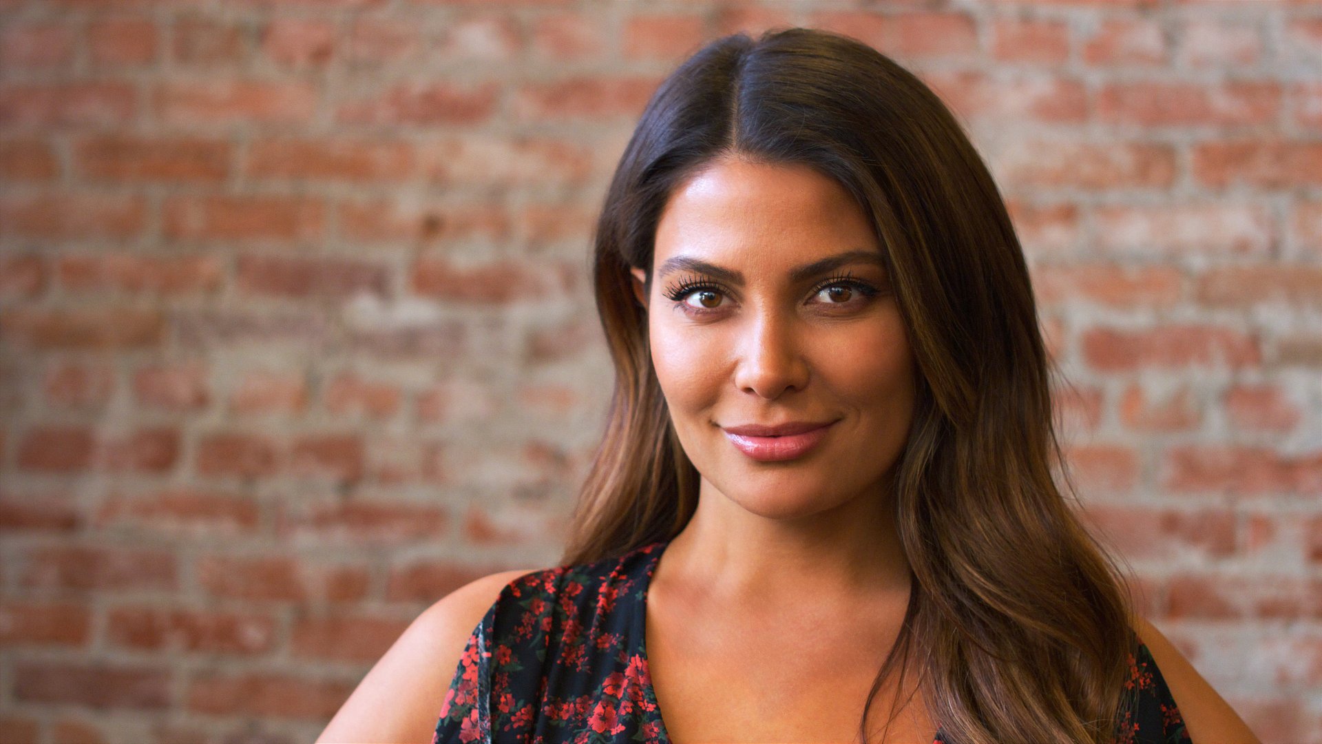 Portrait Of Smiling Hispanic Woman Standing Against Brick Wall In Coffee Shop