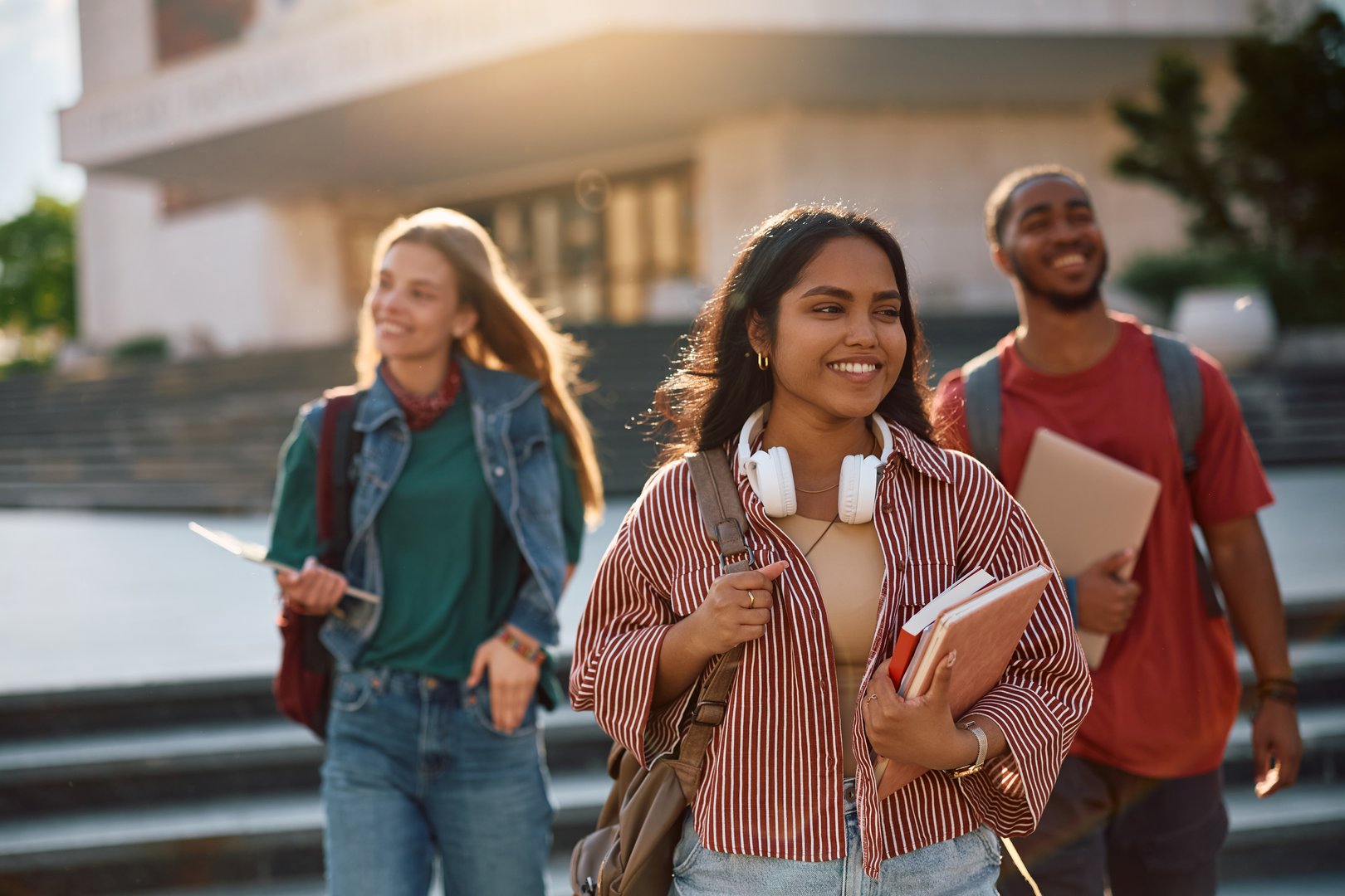 Happy Indian student going on a lecture at the university. Her friends are in the background.