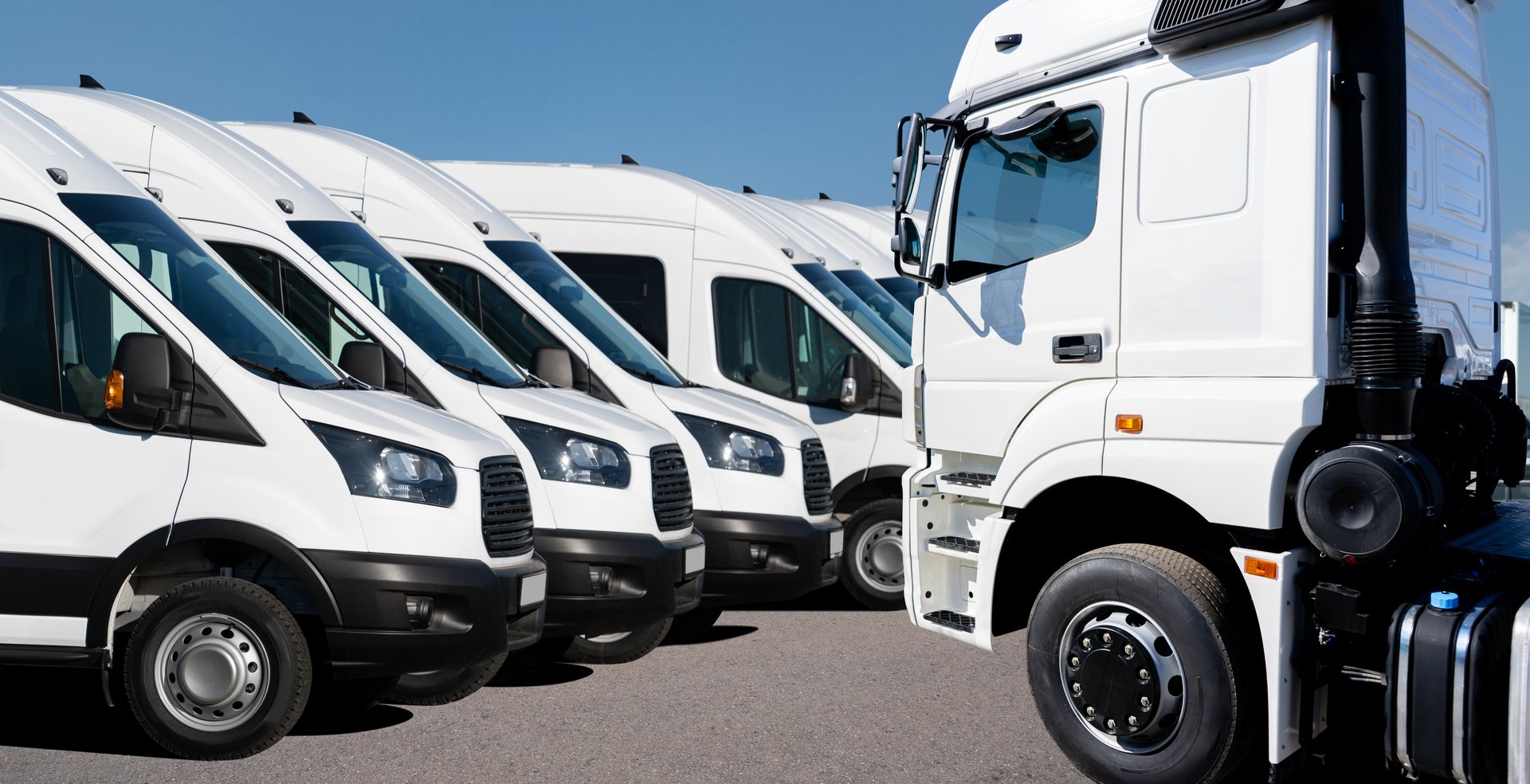 Camión semirremolque y camionetas de entrega de flota en el centro logístico. Muchos camiones estacionados en fila.