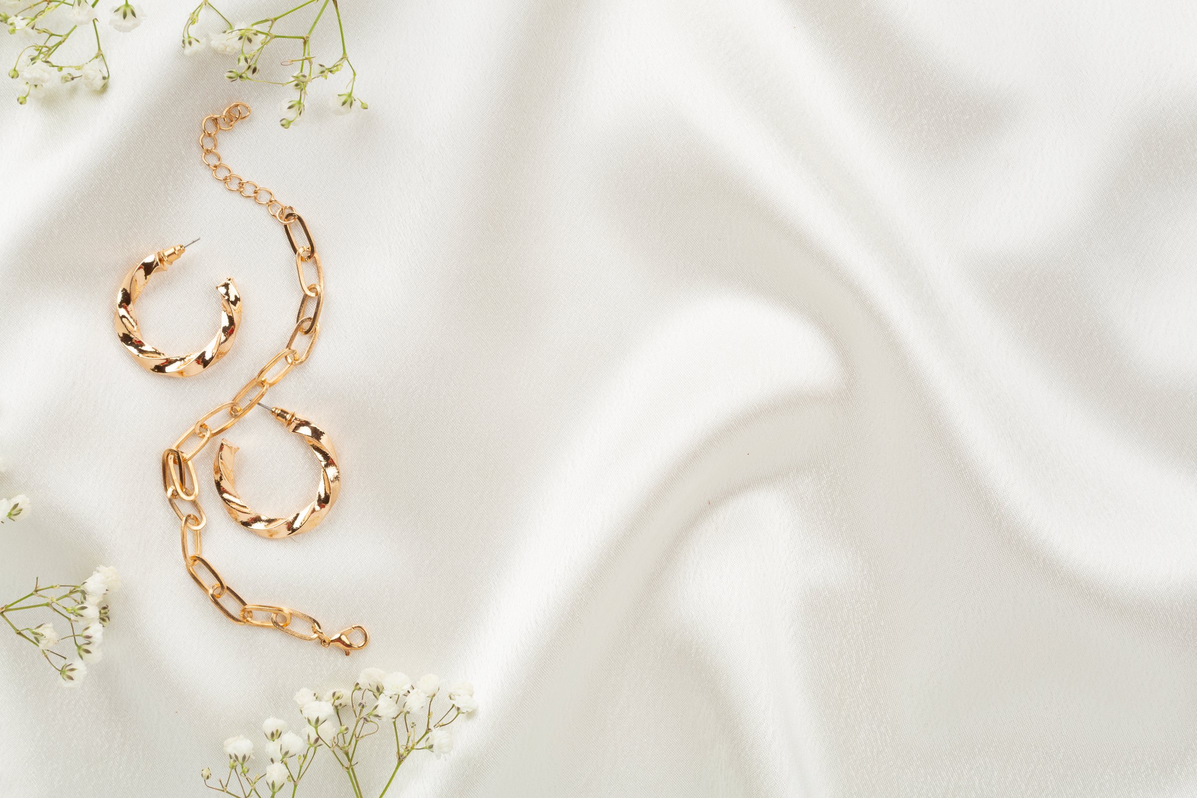 Elegant golden jewelry with decoration on textile background, top view