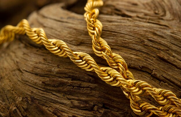 Close-up of a gold twisted rope chain on a textured wooden surface.