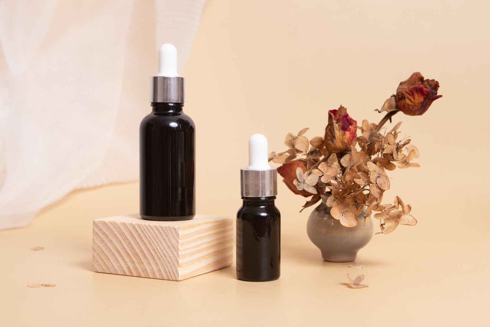 Wooden podium or pedestal with a dropper bottles of cosmetics oil or serum. Neutral beige monochrome skin care concept.
