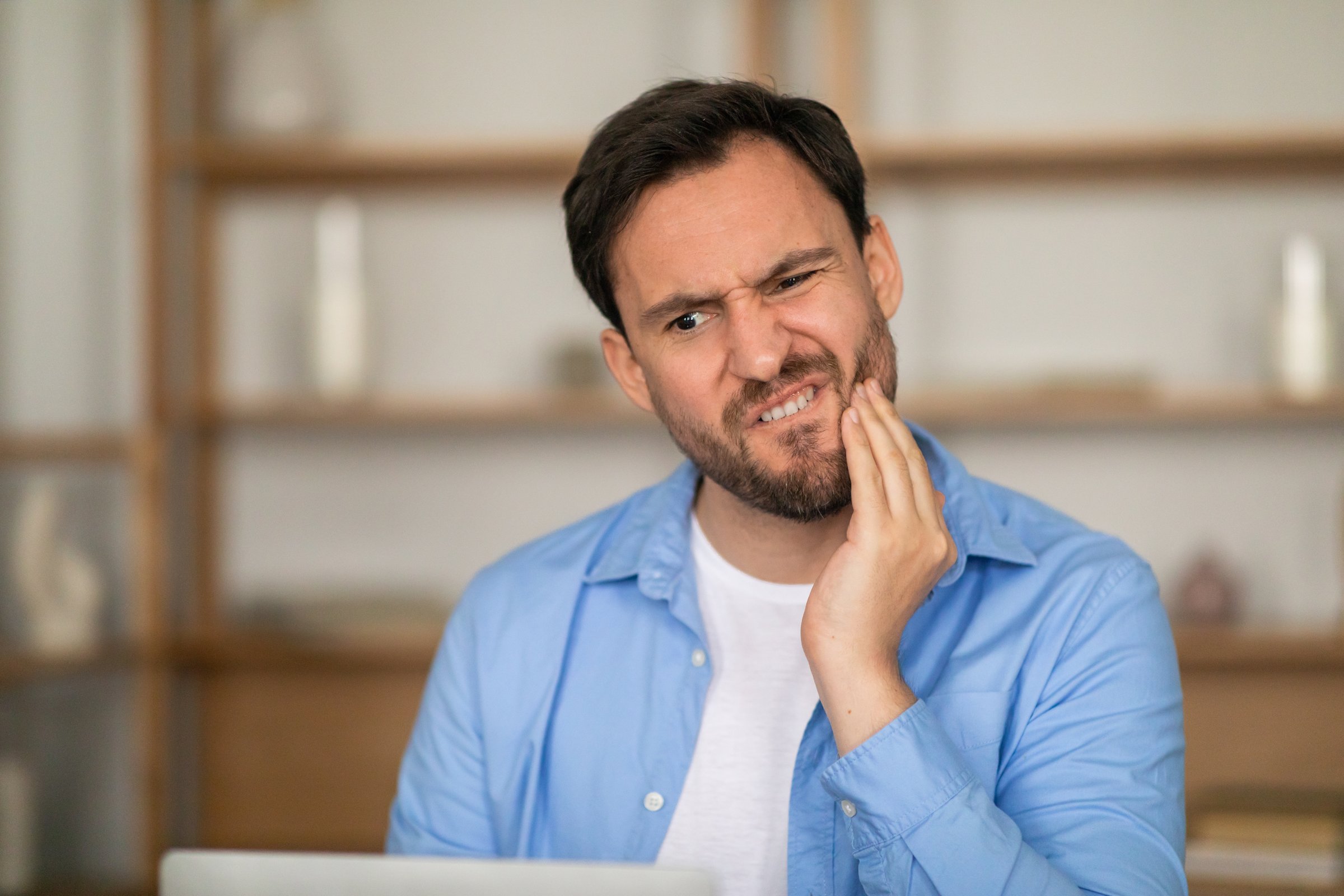 A man holding his jaw in pain due to toothache