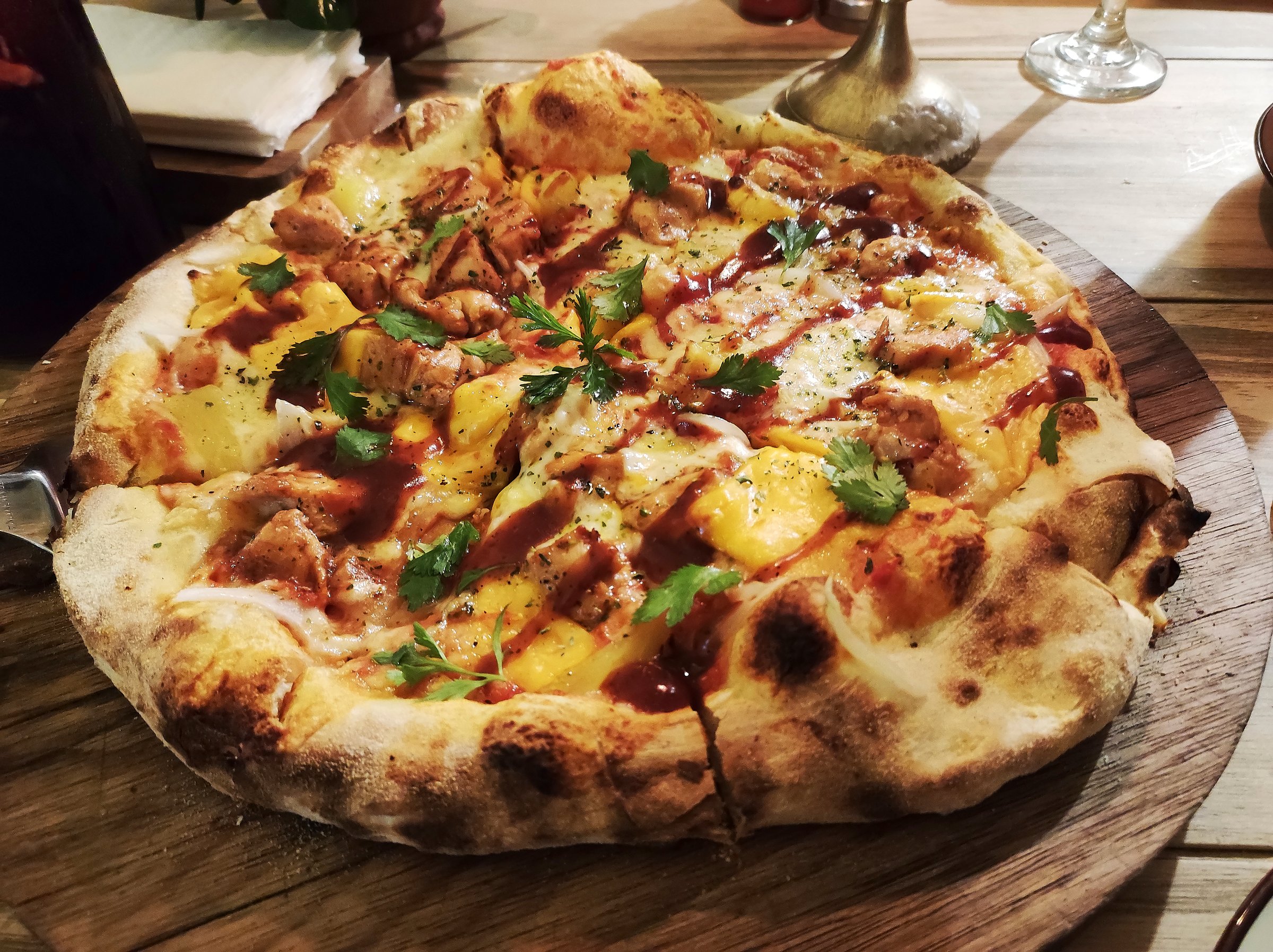 Delicious artisan pizza made in a clay oven and served on a wooden base
