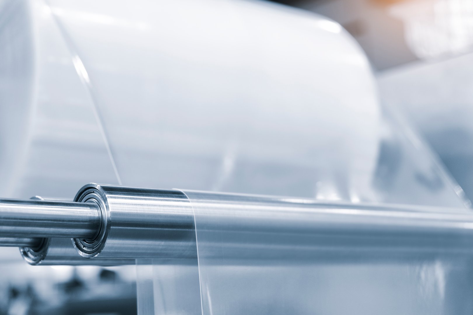 Automatic polyethylene plastic bag production machine with lighting effect. Close-up of the roller of the plastic bag production machine in the light blue scene. product packaging concept