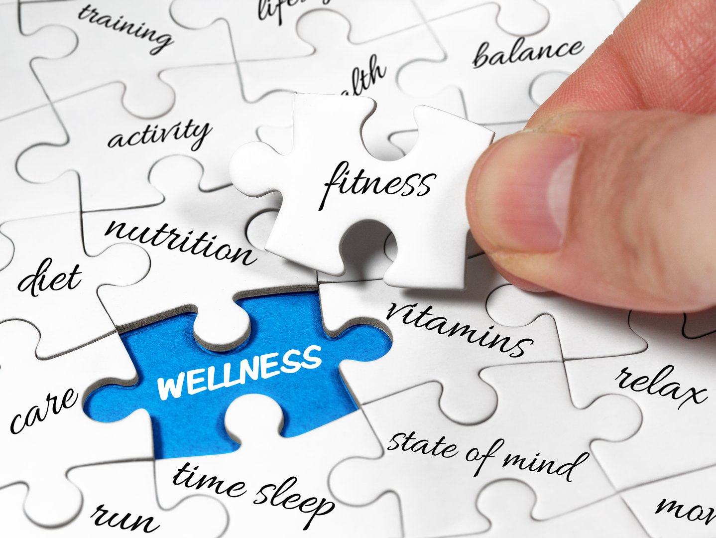 Closeup male hands holding missing jigsaw white piece to complete or solve wellness board puzzle. Fitness is the key concept image