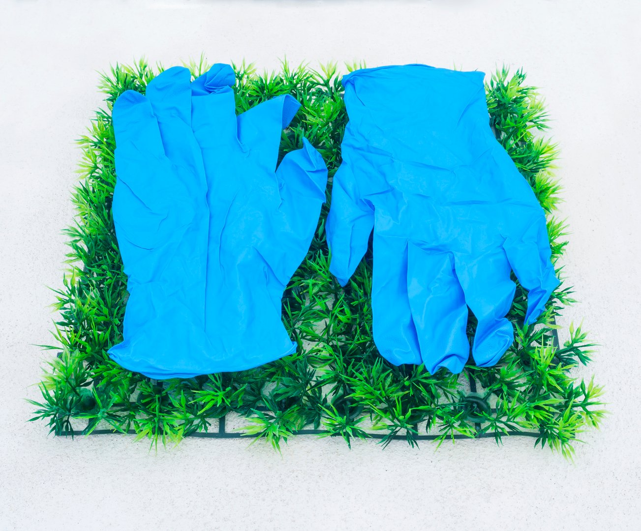 blue rubber gloves on artificial green grass