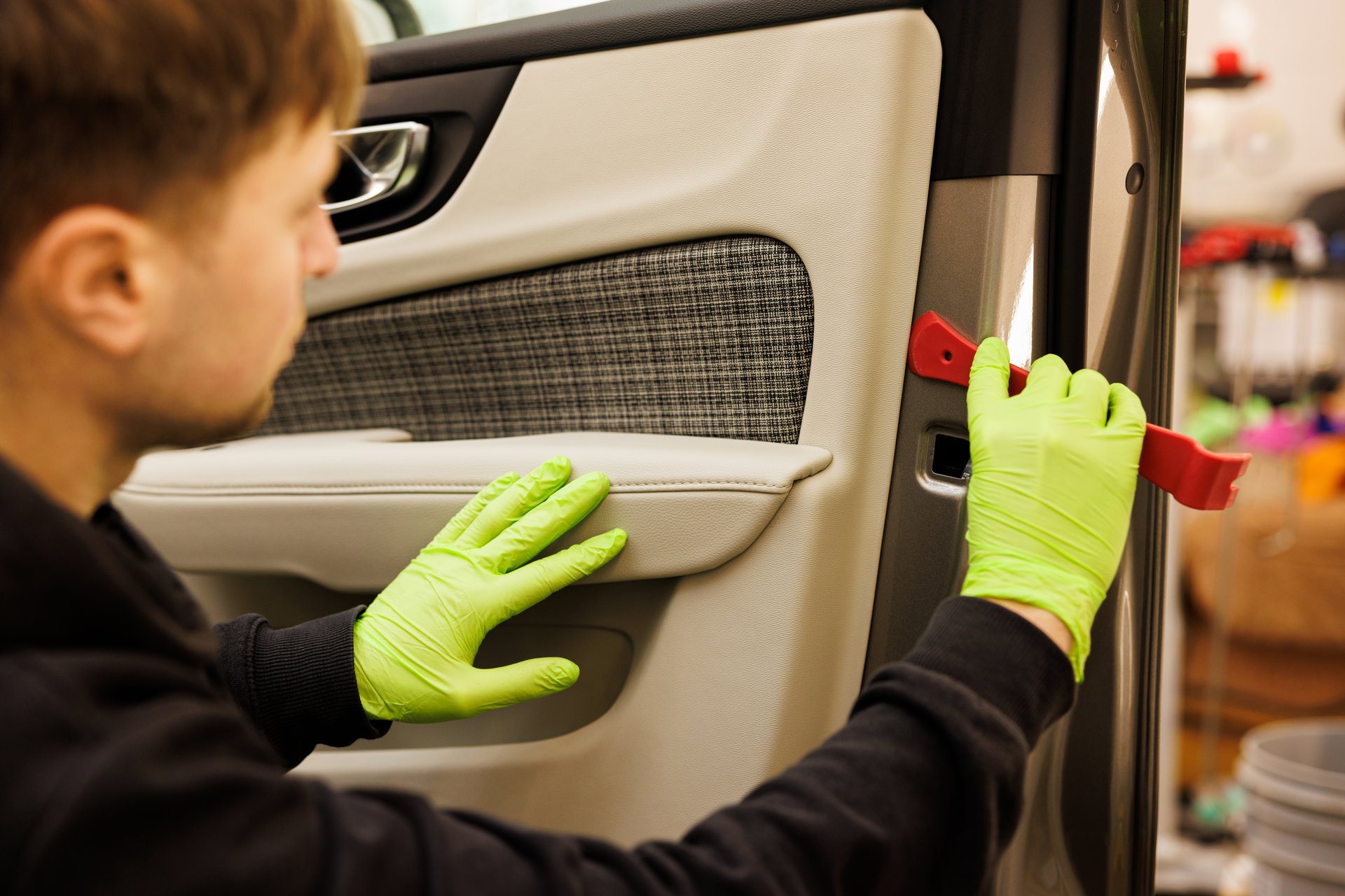 A person in green gloves is cleaning the interior of a vehicle door, showcasing attention to detail in automotive design and maintenance