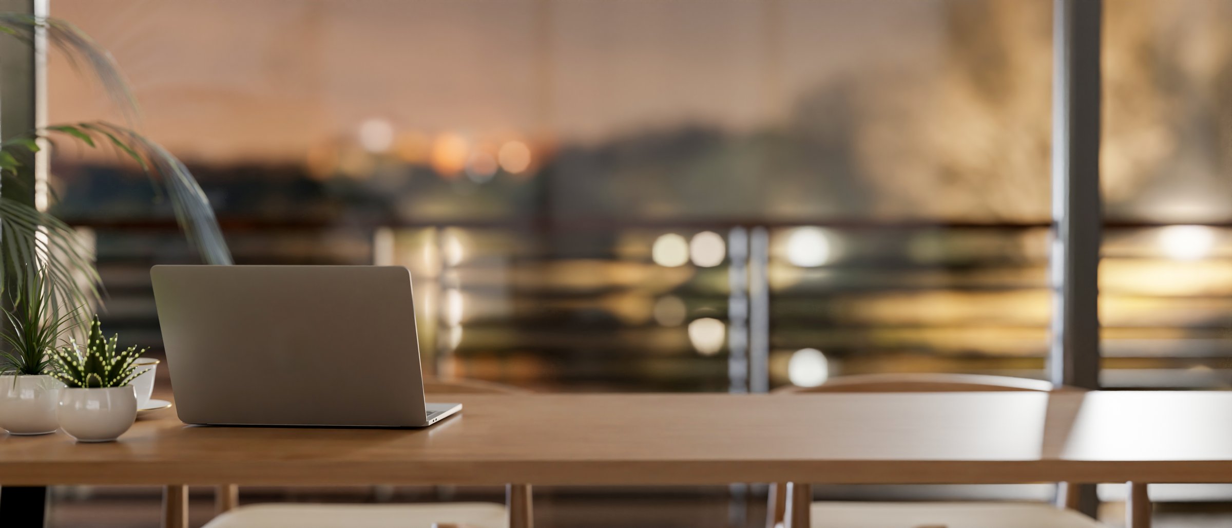 A rear view of a laptop on a wooden tabletop in a room by the window, offering a dusk view through a balcony. 3d render, 3d illustration