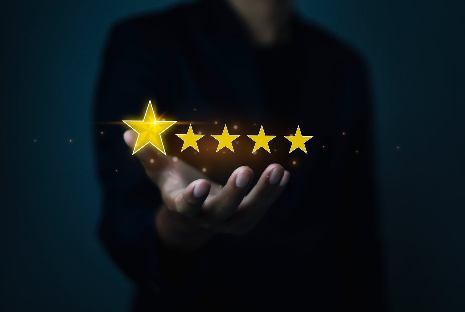 Hand holding five golden stars, concept of customer satisfaction, product quality, service excellence, online review rating, feedback, user experience, and business reputation management.