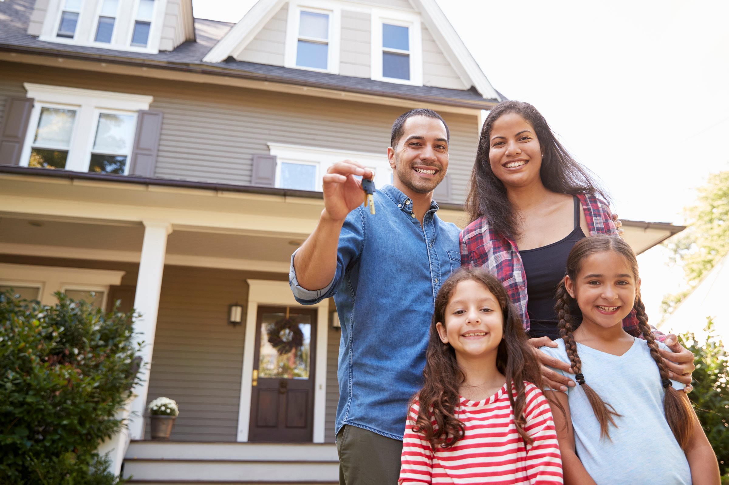 Portrait Of Family Holding Keys To New Home On Moving In Day