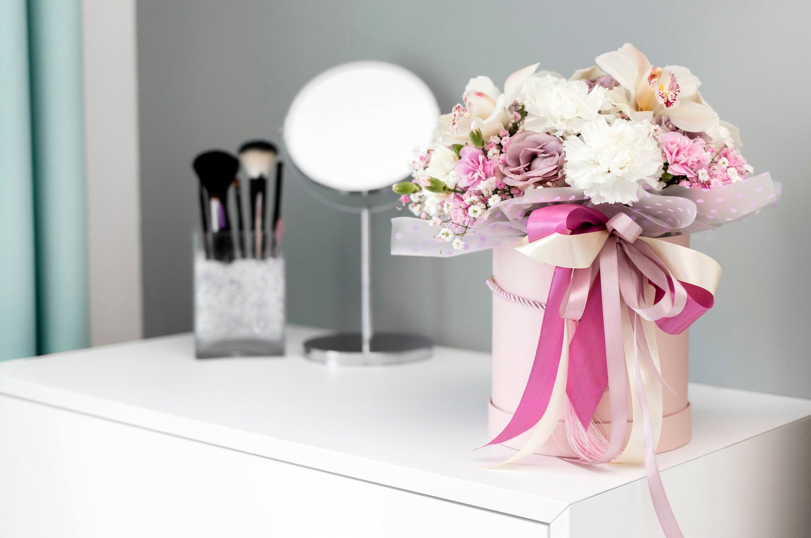 Beautiful flowers in a gift box stand on a dressing table. A gift for a beloved woman. Bouquet for a special event. International Women's Day. Concept of love.