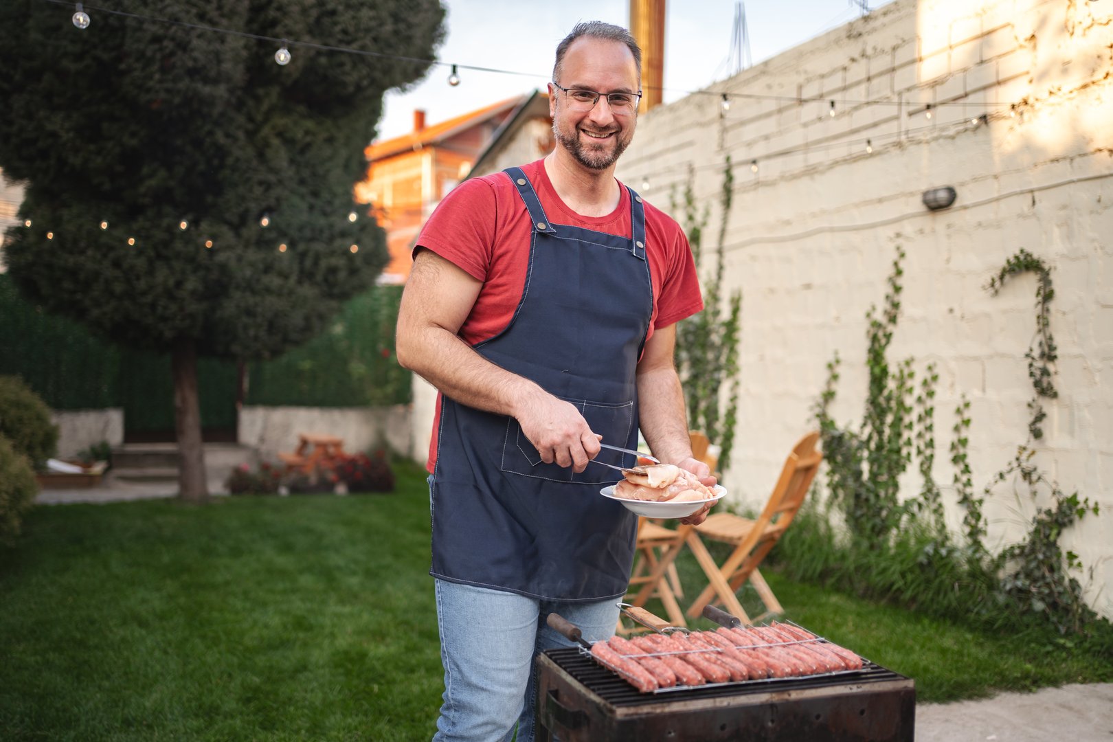 Smiling man grills tasty skewers while preparing for a delightful gathering.