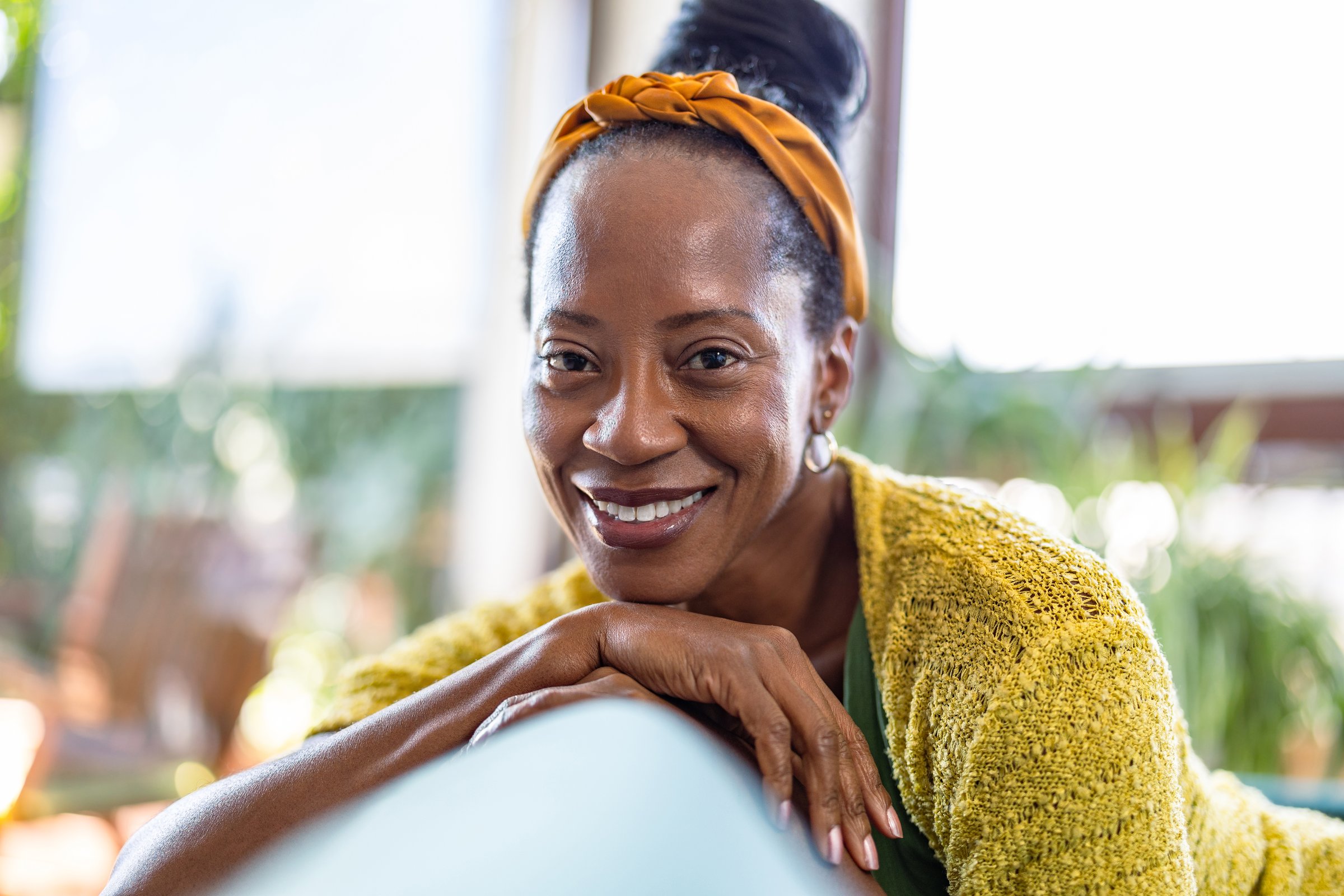Portrait of smiling woman relaxing on sofa at home, looking at camera
