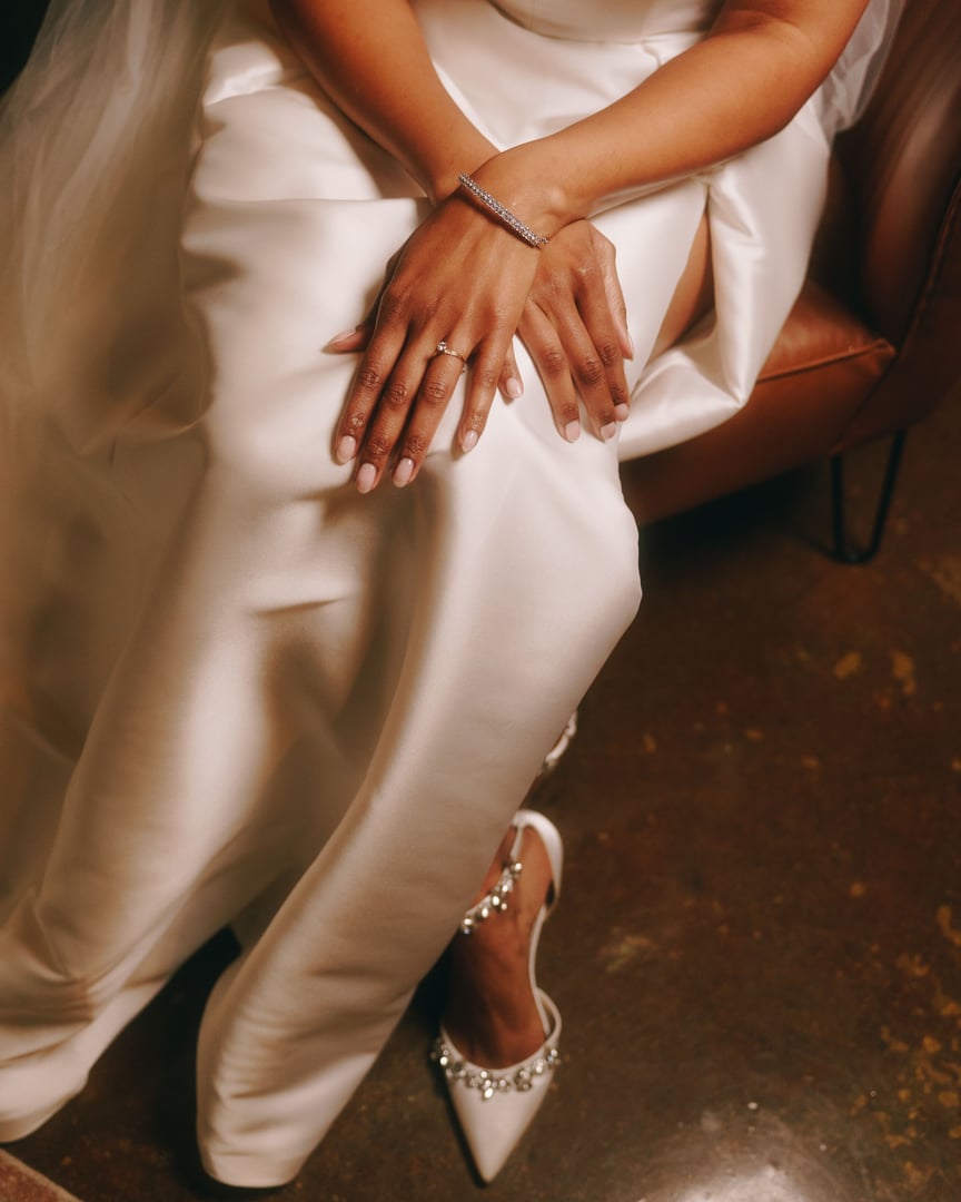 Close-up of a bride's hands on her lap, showcasing a diamond bracelet and ring