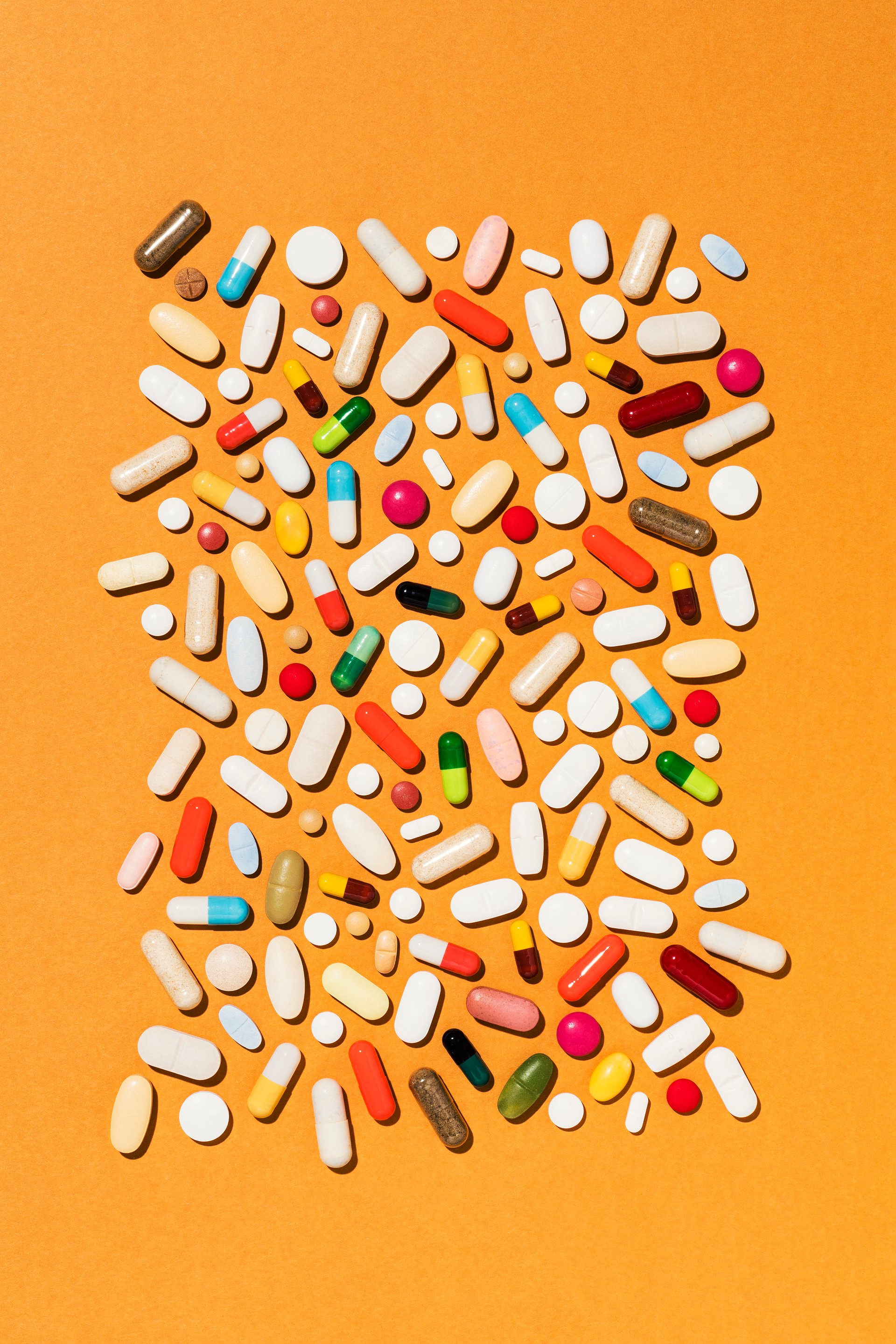 Colorful pills on orange background, directly above medical background