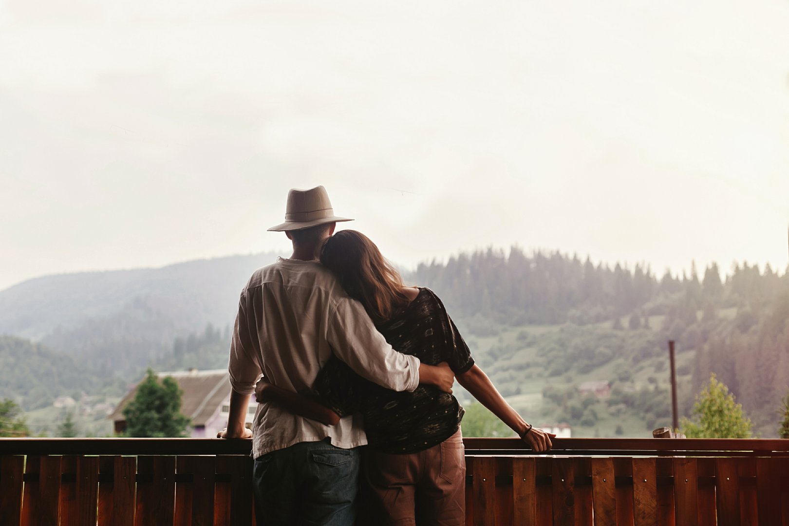 Couple hugging on porch looking at mountains in evening sunset