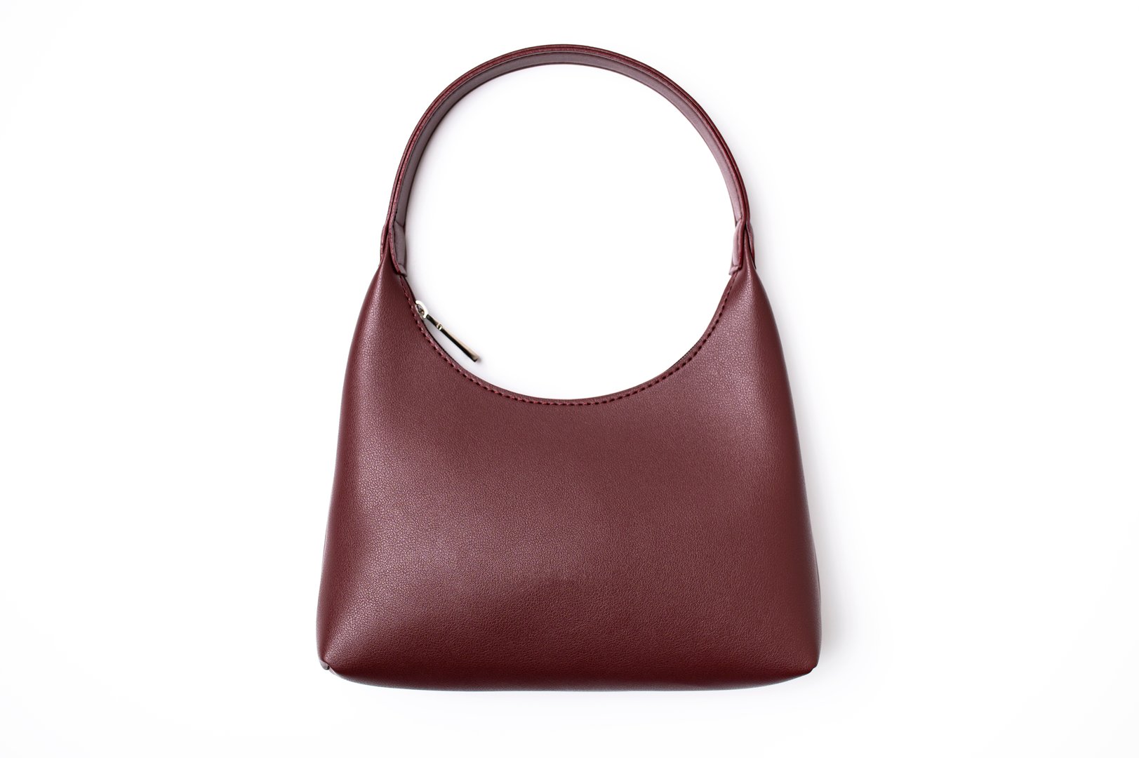 Women's leather bag in burgundy color isolated on white background top view. Fashionable stylish minimalist baguette bag, wine color. Female accessory, object for cutting and design