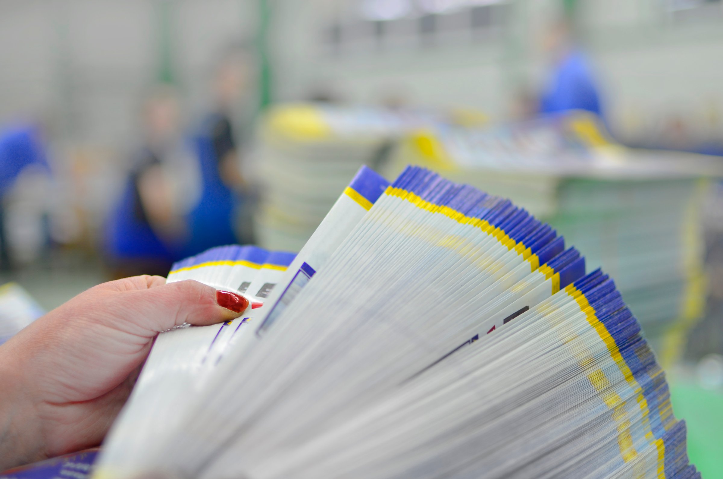 Manual controll and count of printed material packets with blur workers at background