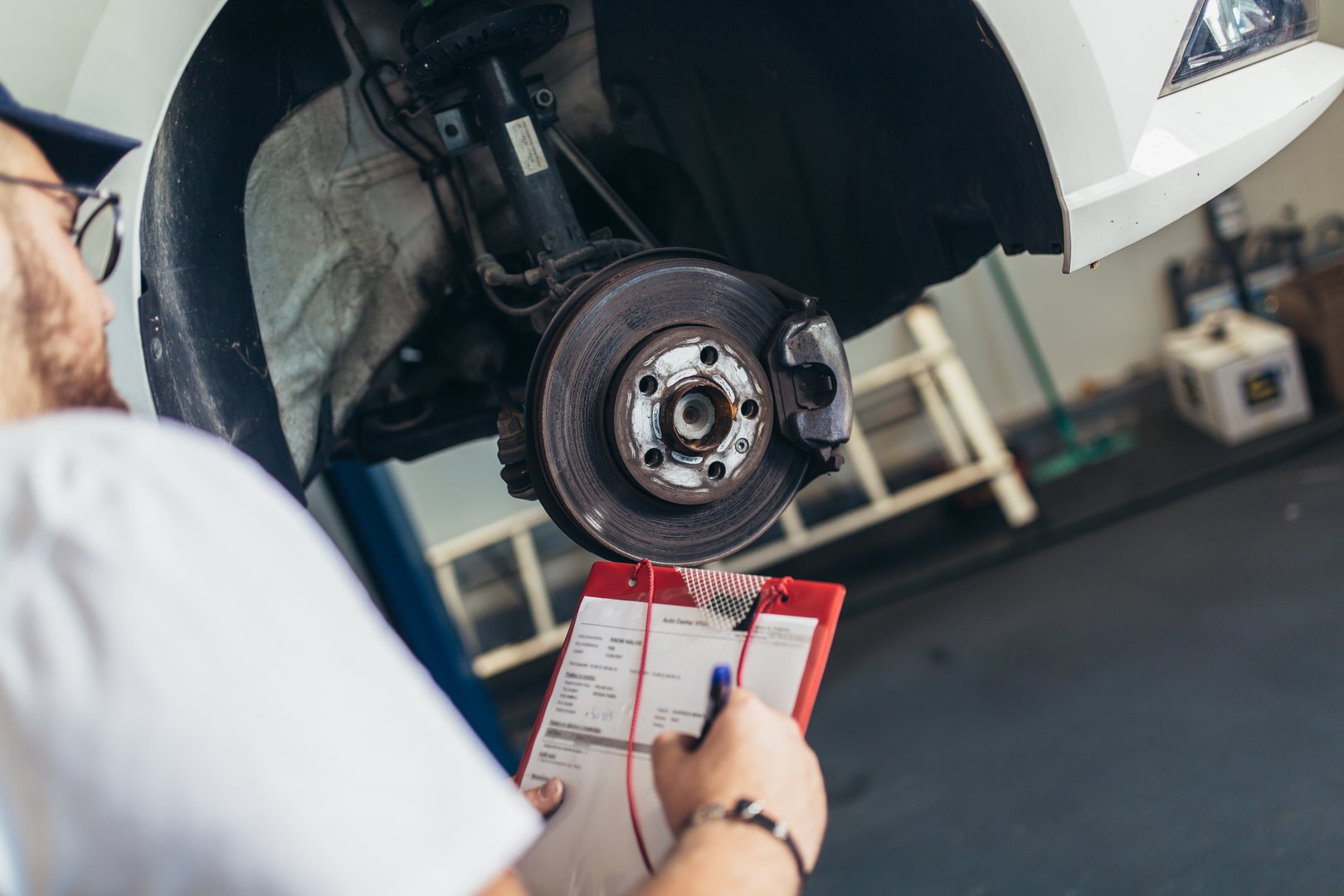 Professional car mechanic working in auto repair service using laptop.