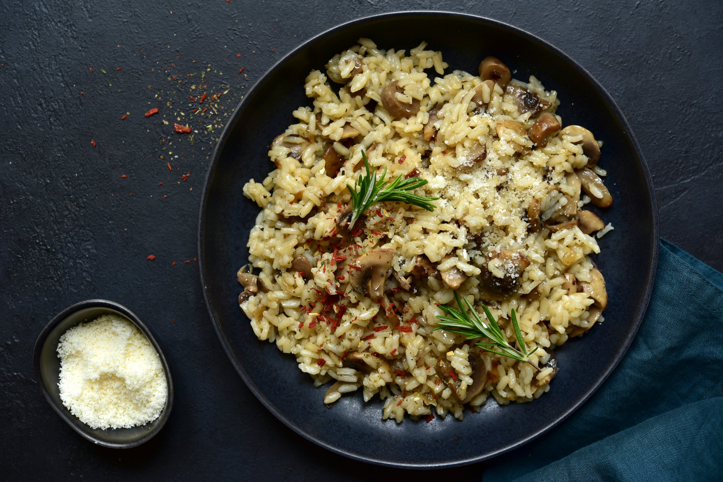 Risotto with mushrooms - tradishional dish of italian cuisine in a bowl over dark slate, stone or concrete background. Top view with copy space.