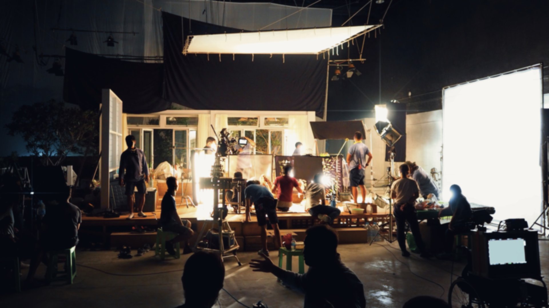 Blurry image of making movie video in big production studio and film crew team shooting or recording by professional digital camera and lighting set equipment.