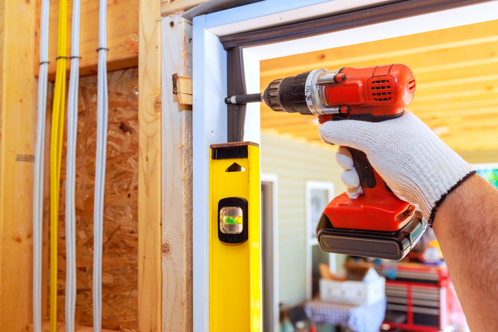 Carpenter uses screwdriver to install front door of new home