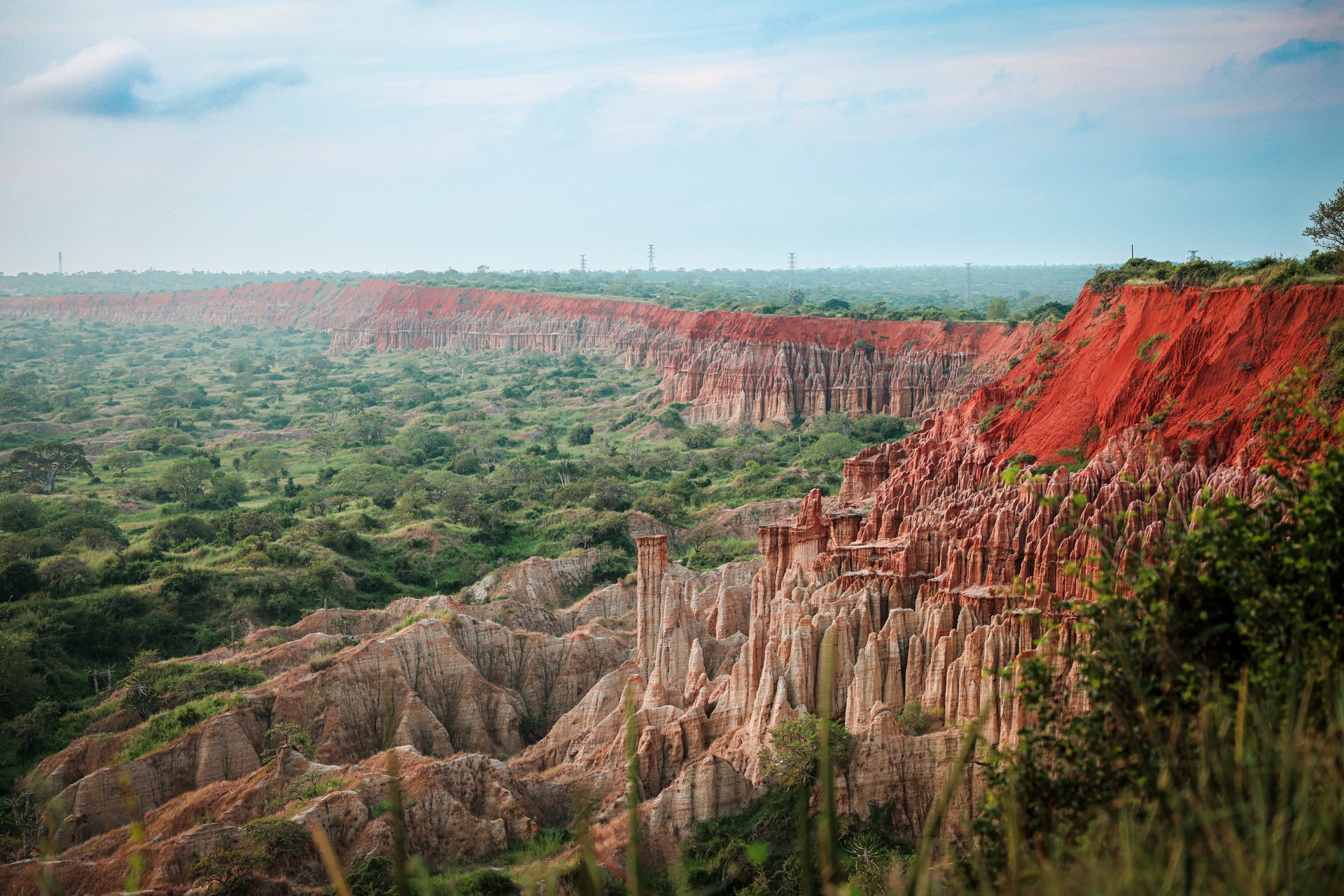 The vibrant red cliffs rise dramatically above a lush green landscape in Angola revealing unique rock formations against a vast sky. This area showcases the natural beauty of the region.