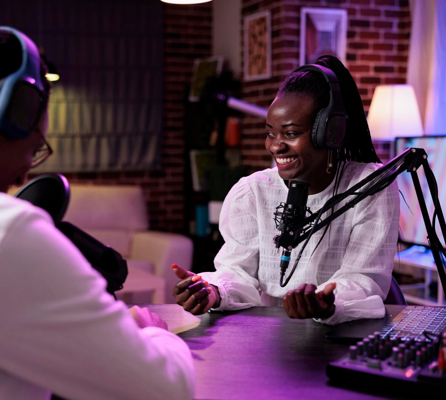 Two people talking in a modern podcast studio with microphones and audio equipment.