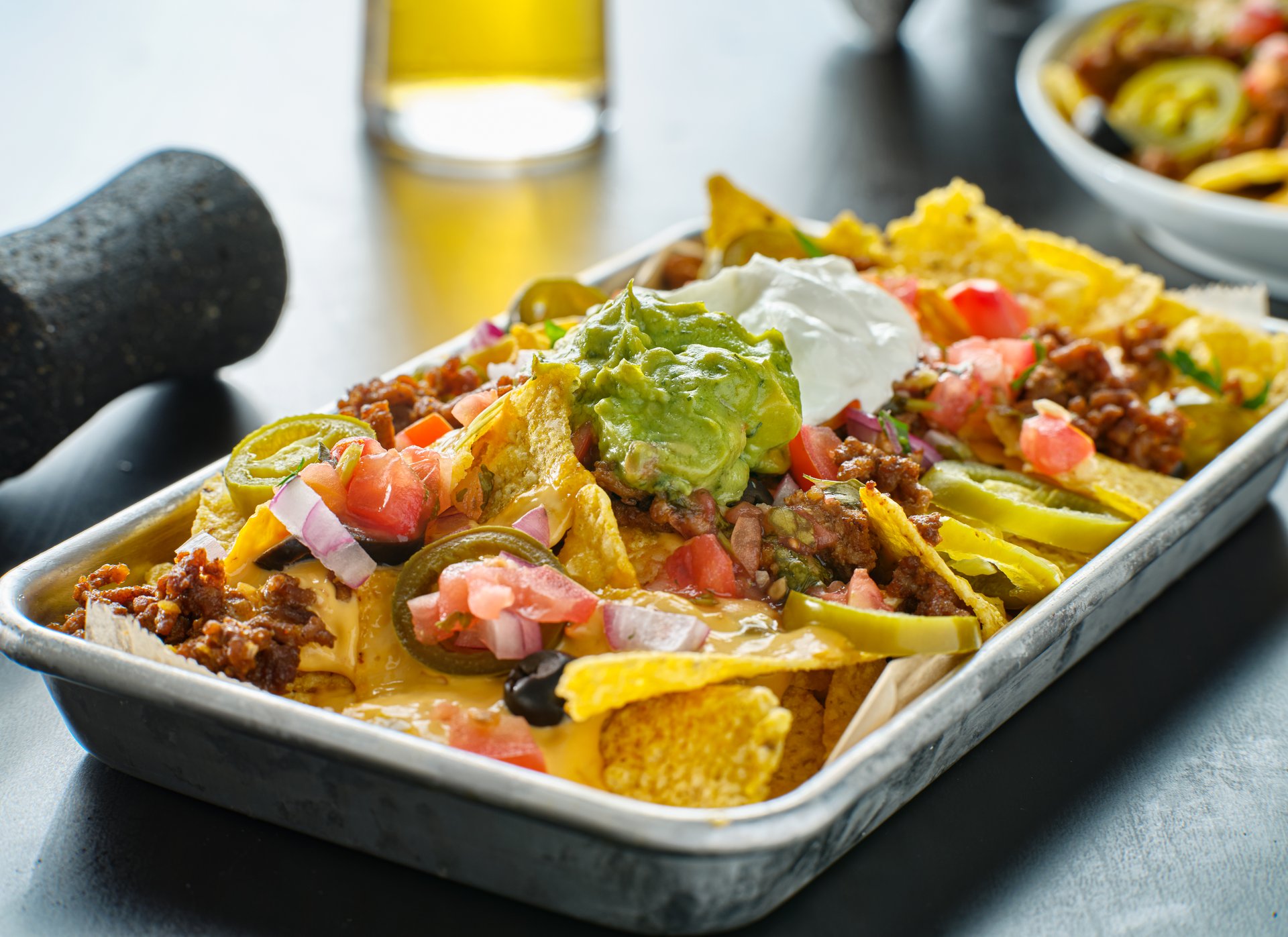 tray of loaded mexican nachos with beef and queso cheese close up