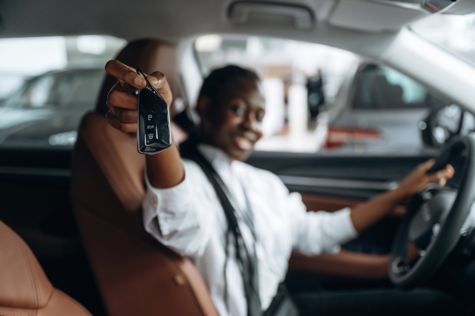 The keys are in hand. Woman in white shirt is in the modern car.