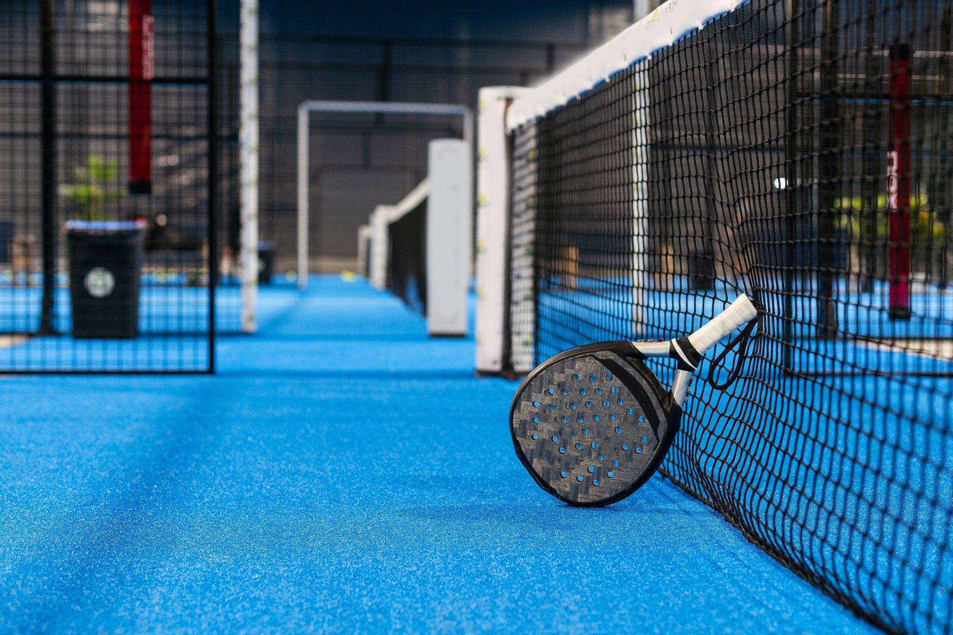 White professional paddle tennis racket with natural lighting on blue background. Horizontal sport theme poster, greeting cards, headers, website and app. High quality photo