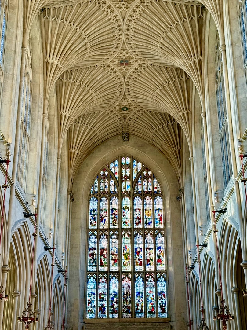 Interior view of Bath Abbey featuring the large stained glass east window beneath the Abbey's distinctive fan vaulted ceiling