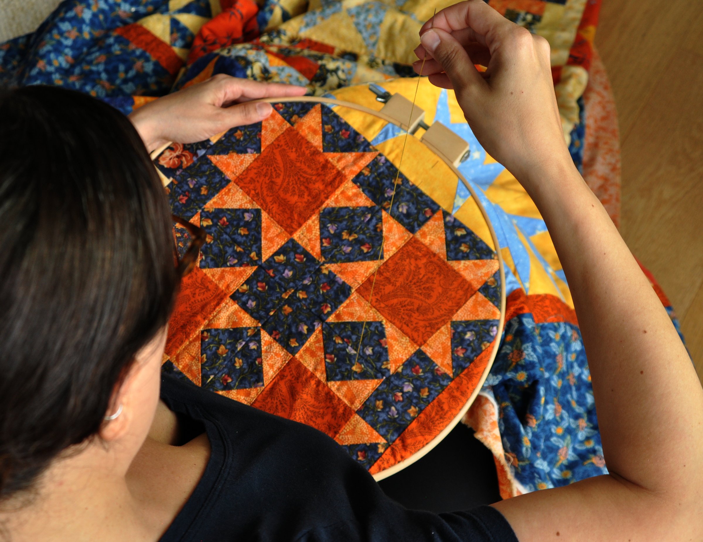 Woman hand sewing a quilt from above