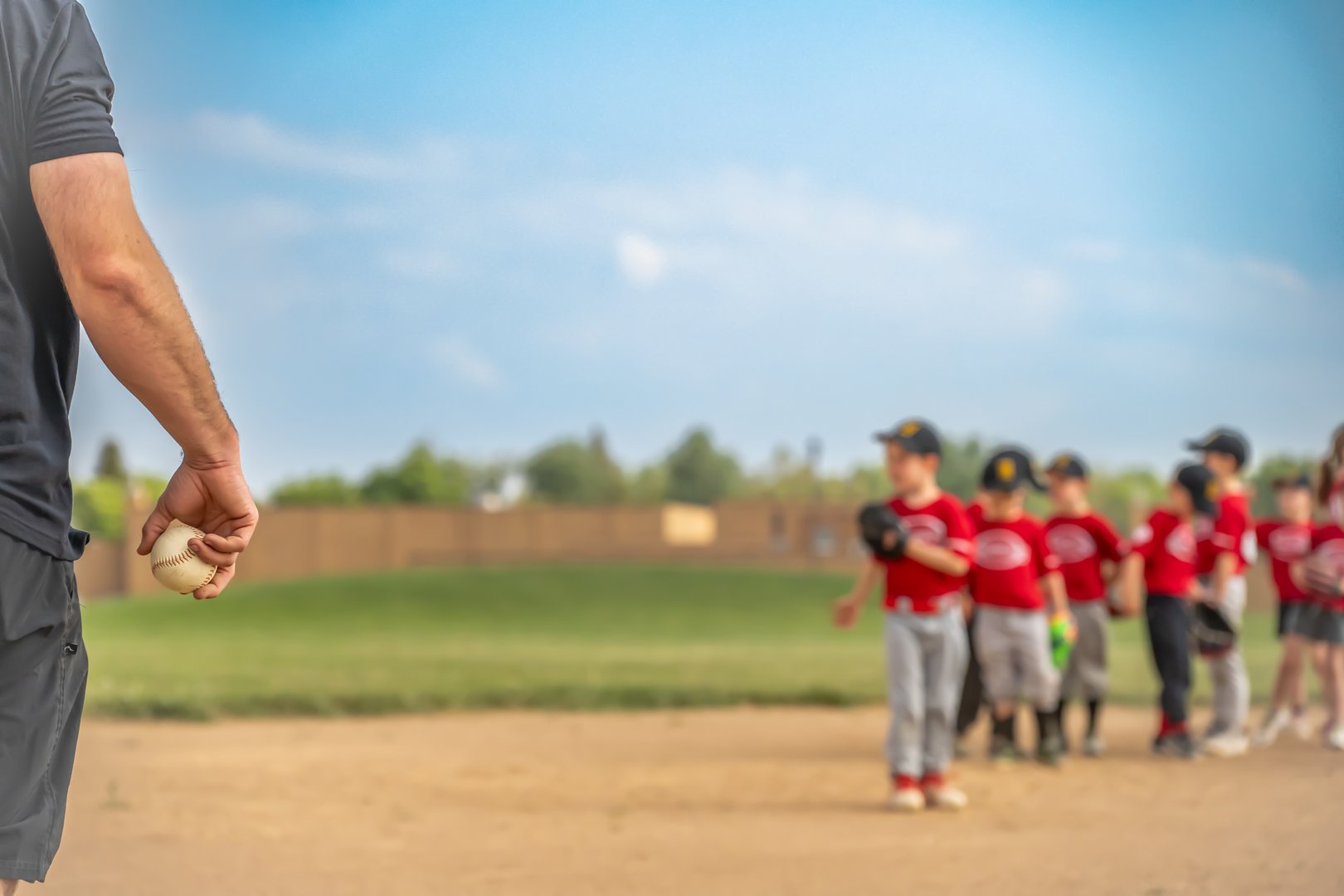 Selective focus on a coach getting ready to toss a ball to a child during practice . High quality photo