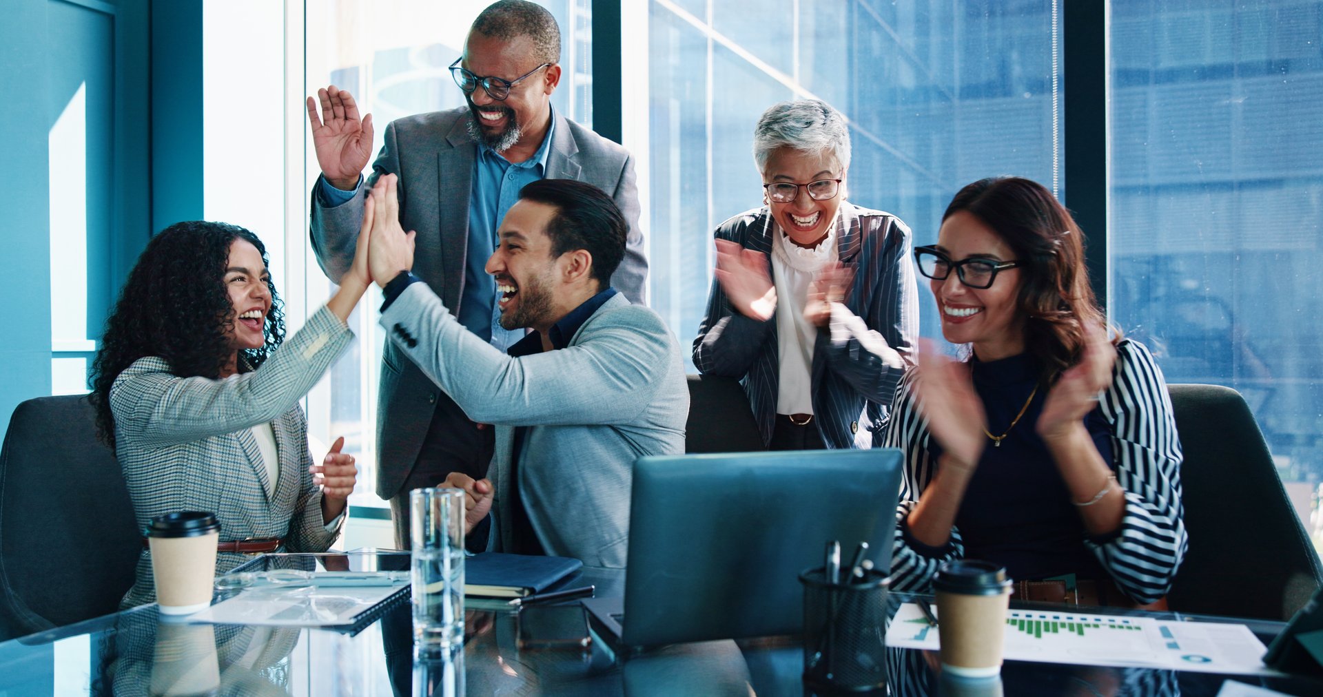 Applause, high five and success with business people in boardroom of office together for celebration. Bonus, milestone and victory with employee group in workplace for goals, motivation or target