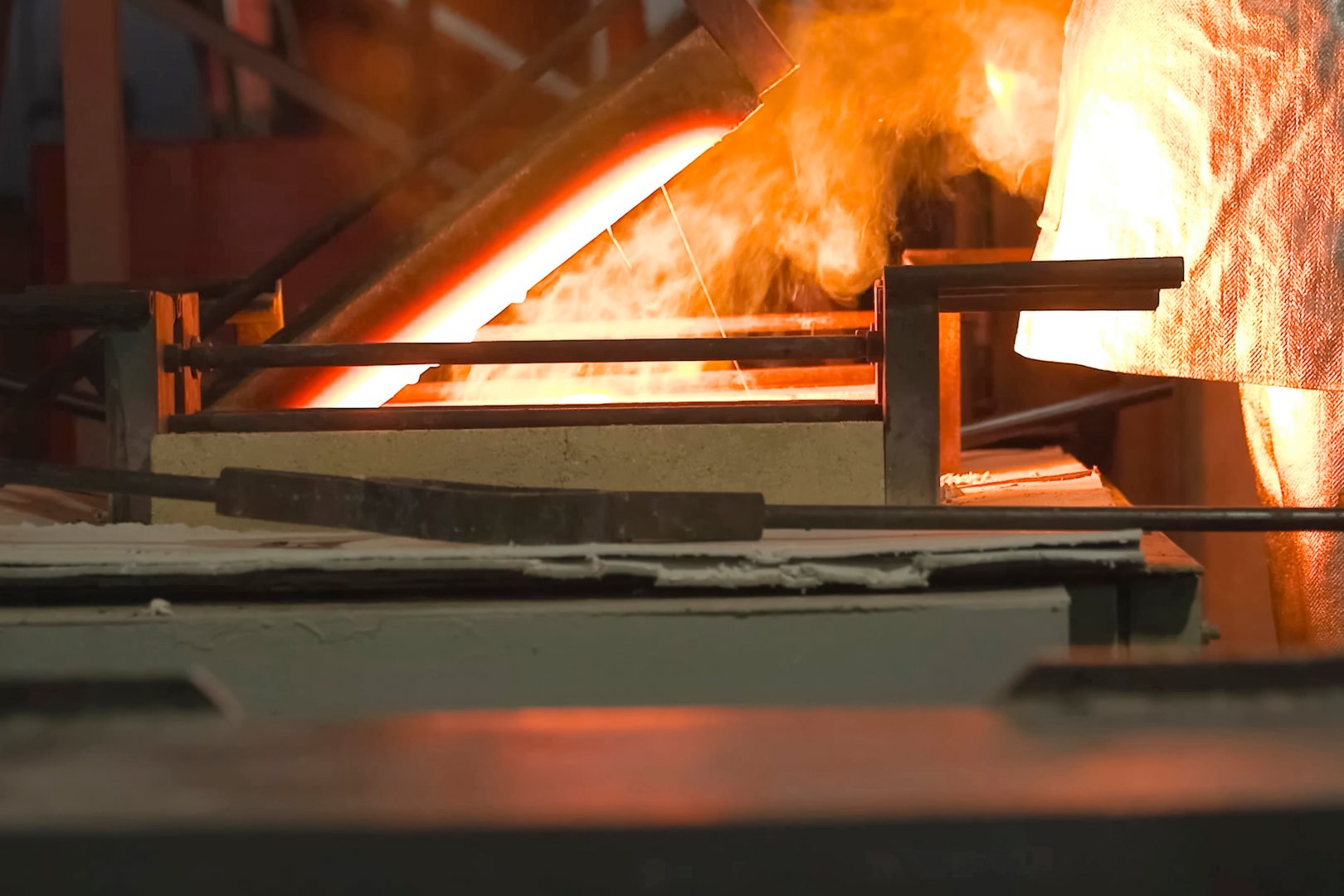 A worker in a heat-protective suit looks into the melting furnace to control the melting of gold.