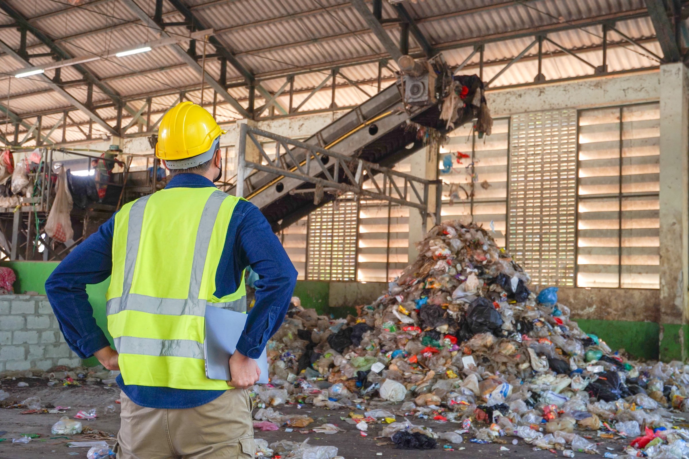 Behind is an environmental engineer checking the sorting of waste at a waste sorting plant.