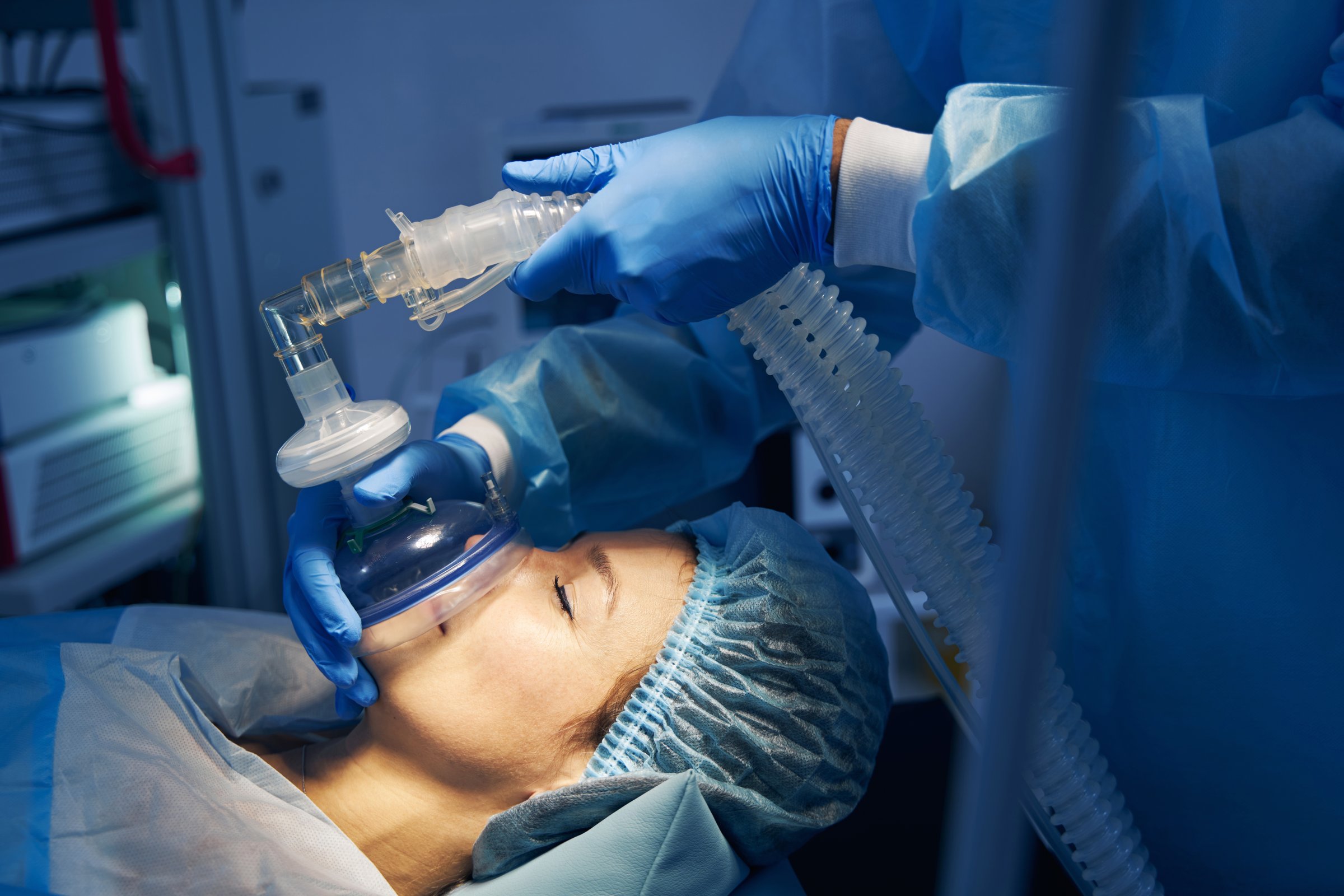 Woman on the operation table getting anesthesia before the surgery. Doctor in medical clothes standing near
