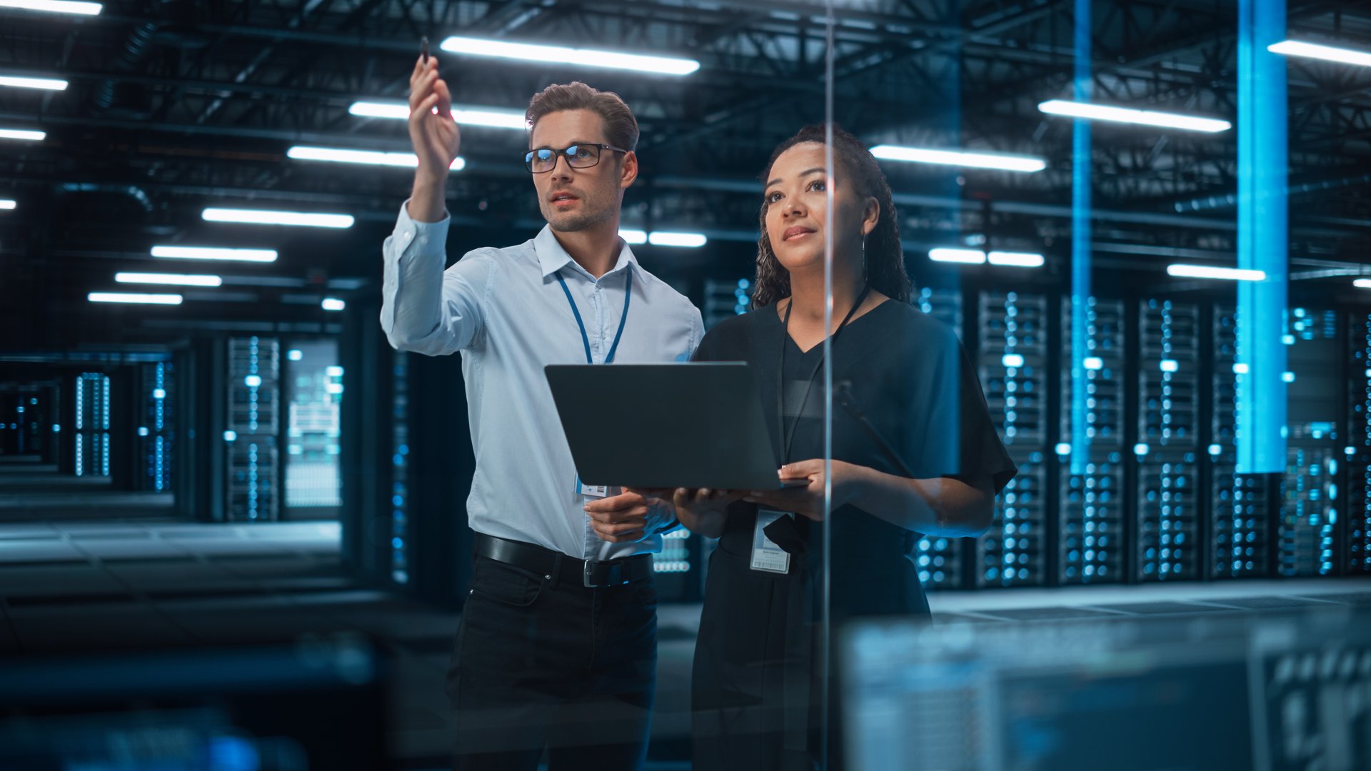 Information Technology Engineer and System Administrator Monitoring Web Services Cloud Solution Software and Sharing Ideas with Each Other in Big Data Center Server. People Use Laptop.