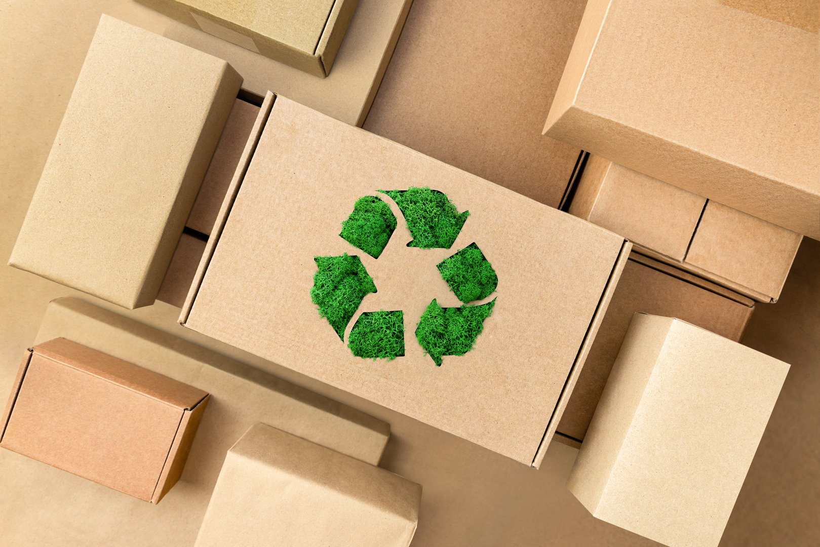 heap of cardboard boxes and one with a green recycling sign in the center, top view