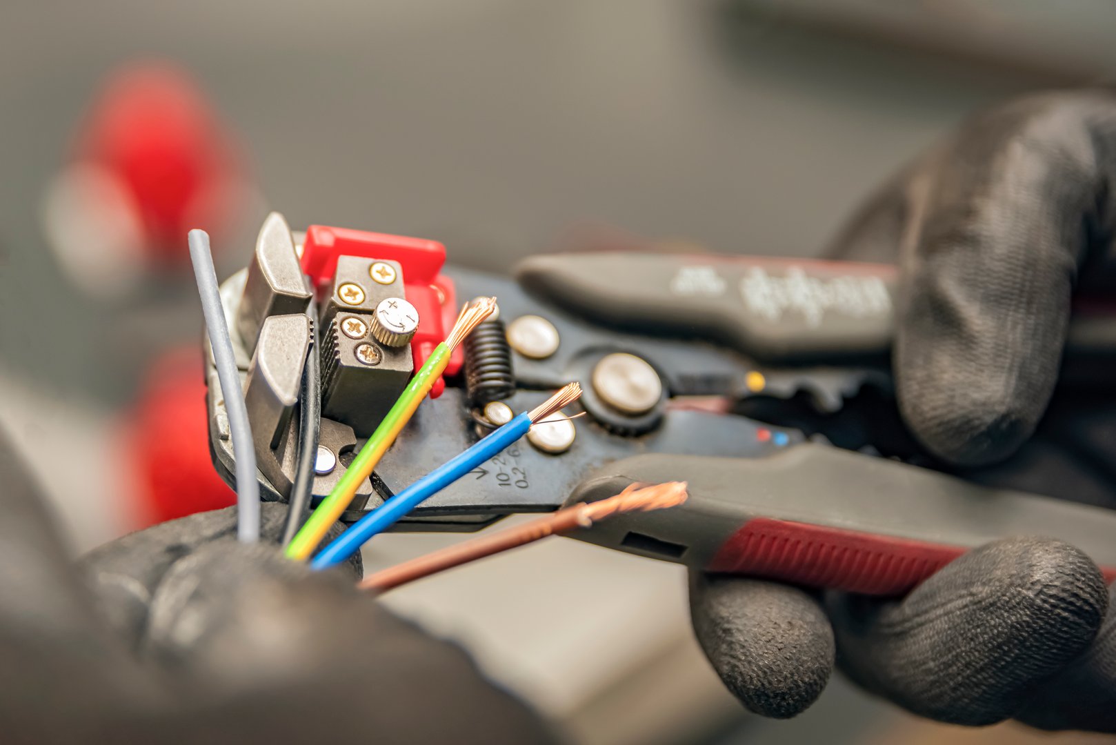 Wire strippers. The electrician cleans the protective insulation from the wire using a wire stripper. The process of connecting wires. close-up.